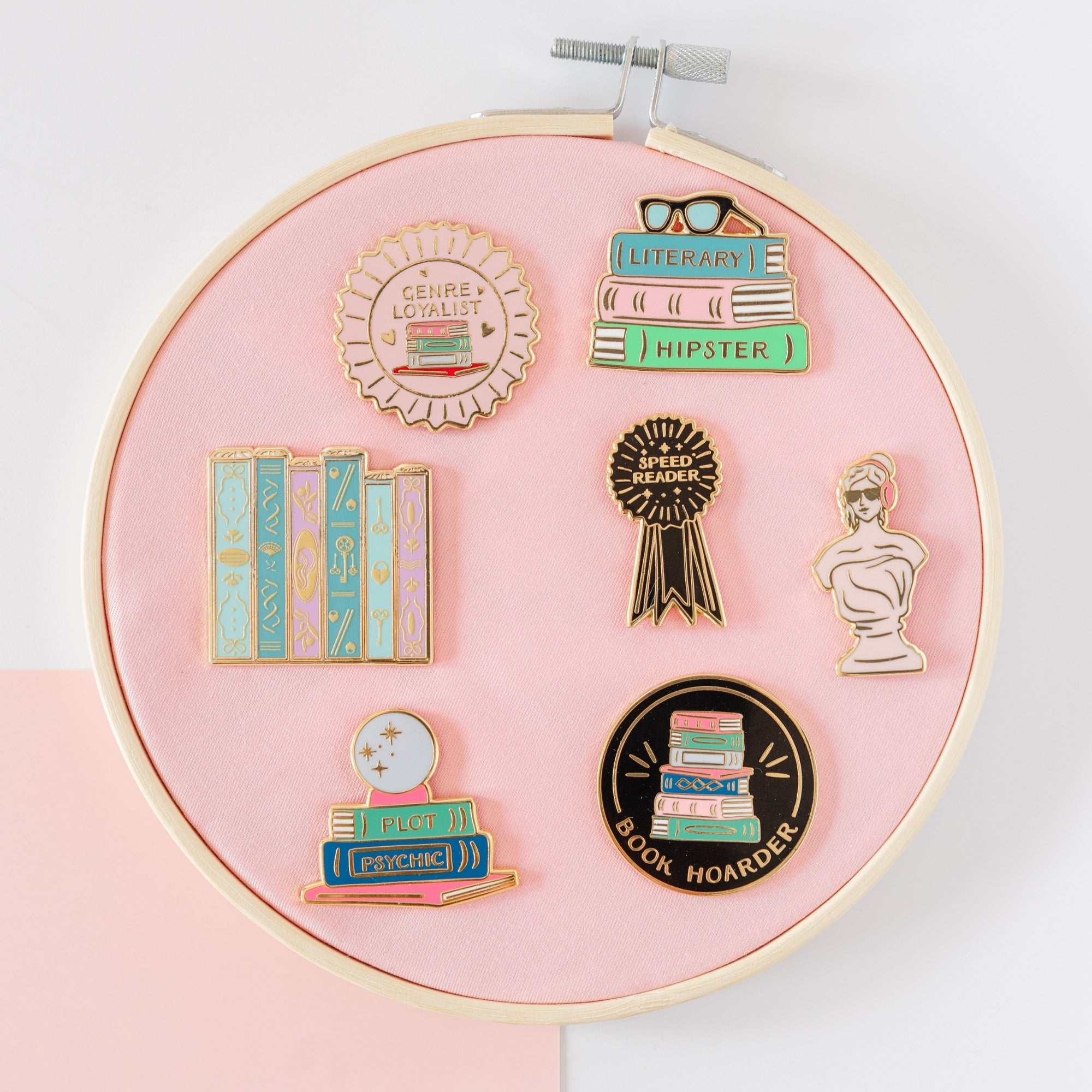 Book-themed enamel pins collection display showing literary personality pins including bookmarks and characters, Jollity & Co.