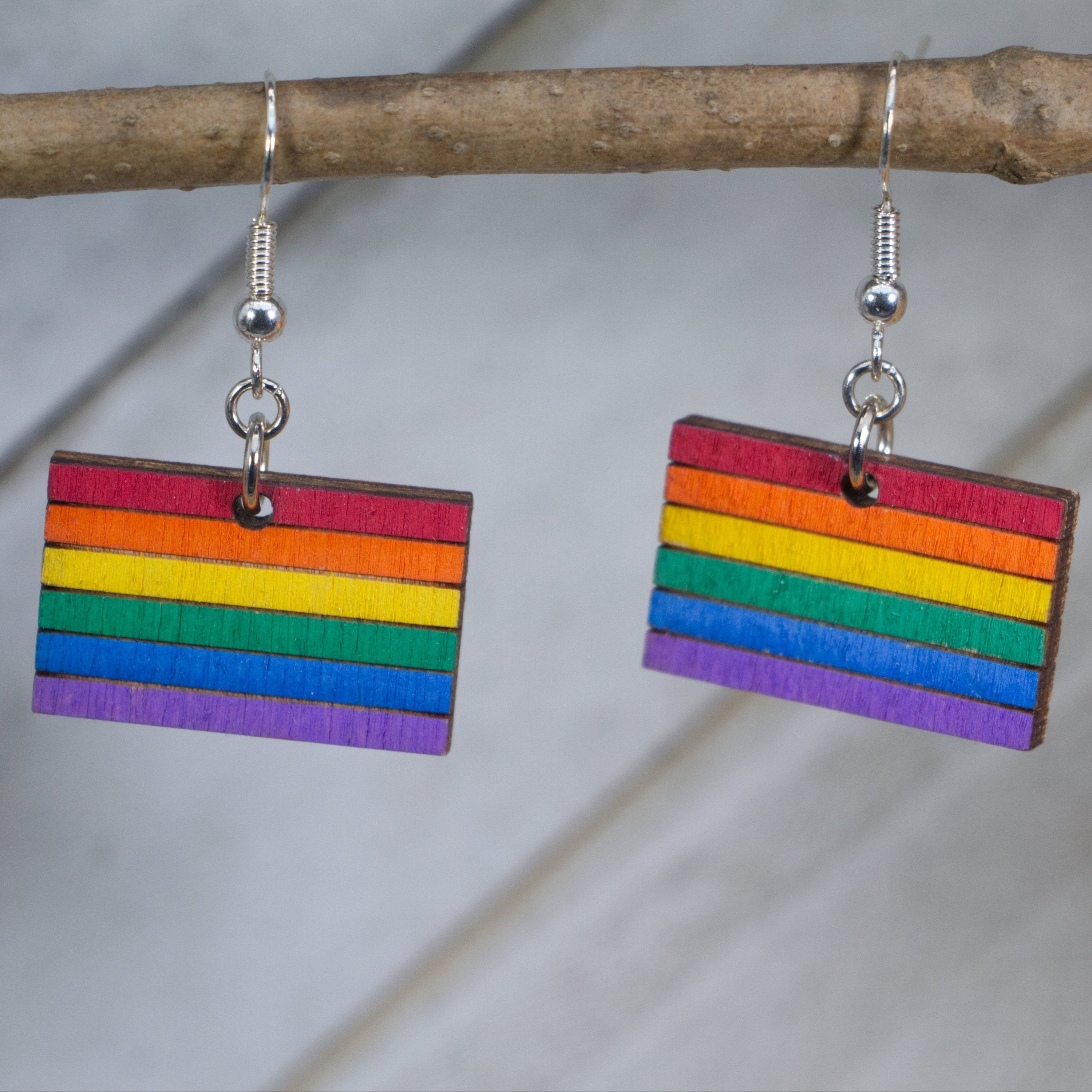 Hand-painted wooden LGBTQ pride flag dangle earrings with vibrant rainbow design and hypoallergenic sterling silver hooks, lightweight equality statement jewelry for pride events and everyday expression