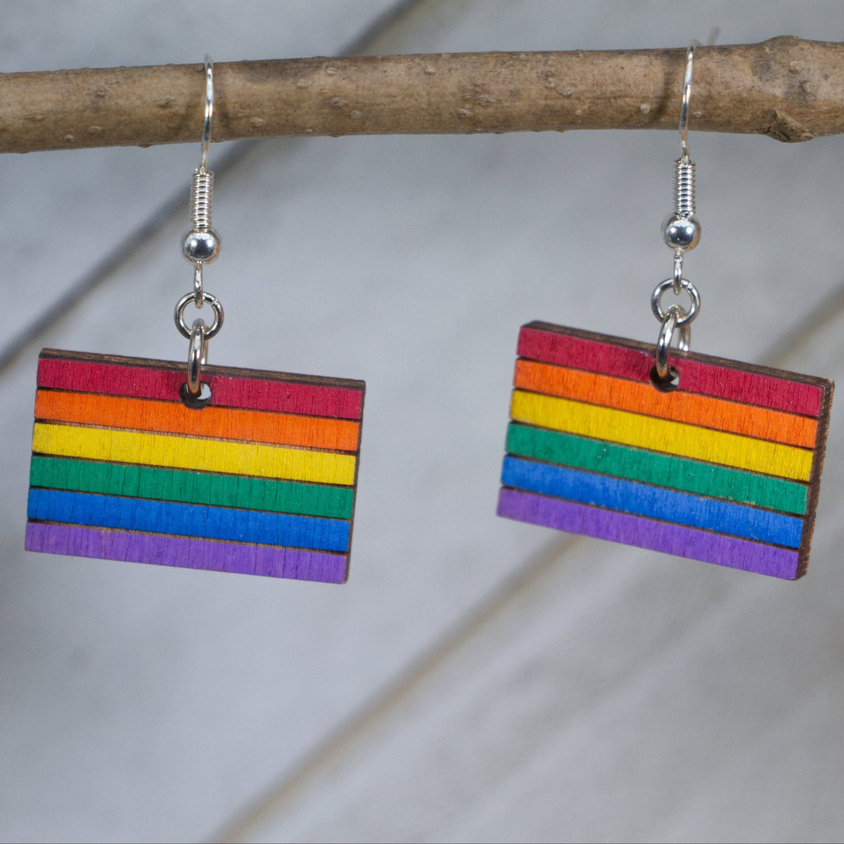 Hand-painted wooden LGBTQ pride flag dangle earrings with vibrant rainbow design and hypoallergenic sterling silver hooks, lightweight equality statement jewelry for pride events and everyday expression