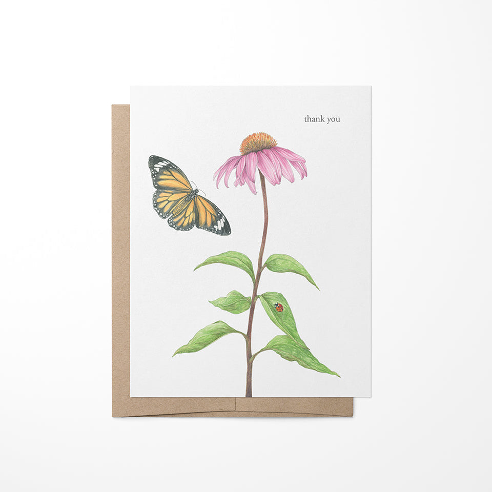 A greeting card with a watercolor painting of a pink echinacea flower and a monarch butterfly on it, with a beige kraft envelope.