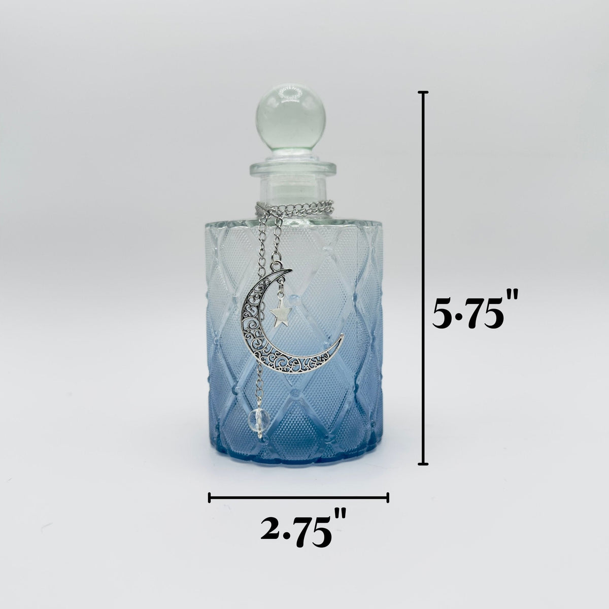 A small glass bottle with a rounded stopper, shown on a light gray background with black dimension lines indicating 5.75 inches tall by 2.