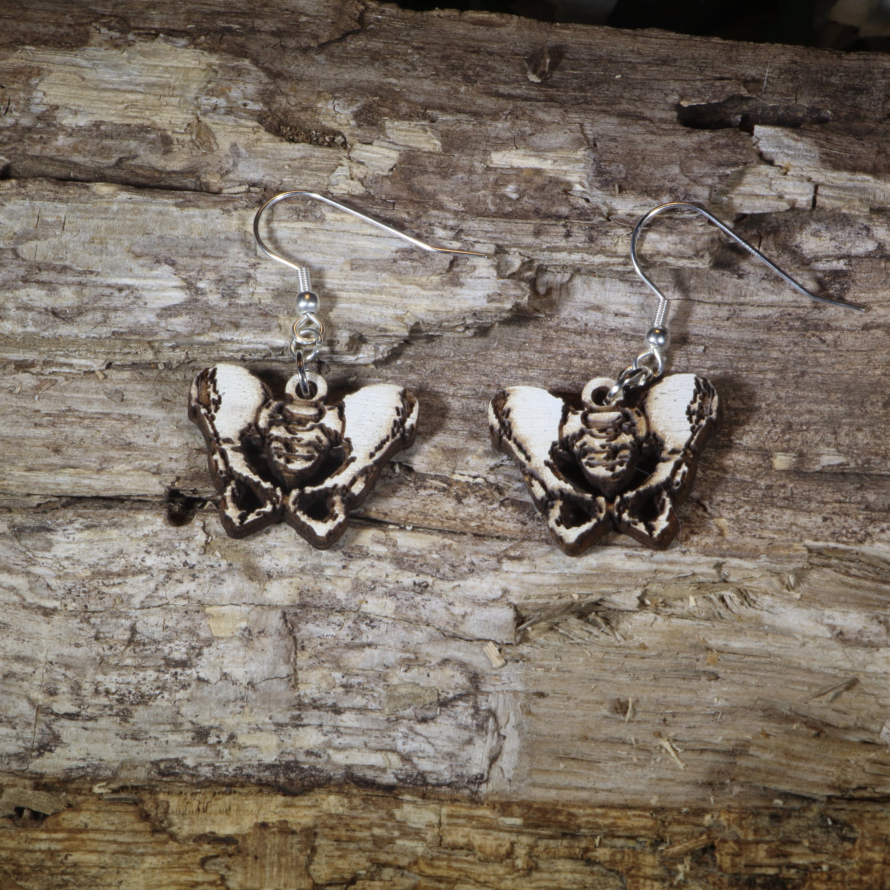 Hand-painted wooden pelvis anatomy dangle earrings featuring an anatomical pelvis design with lightweight construction and hypoallergenic .925 sterling silver hooks, perfect for doctors, nurses, physical therapists, chiropractors, medical students, and healthcare professionals.