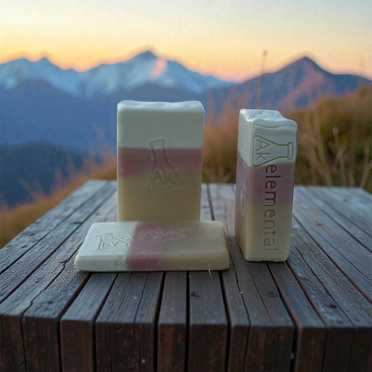 Three soaps sitting on a wooden railing.
