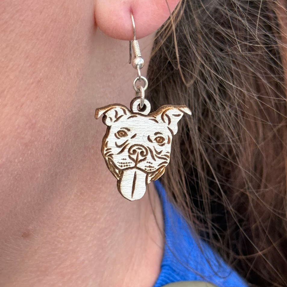 Woman wearing hand-painted wooden pitbull face dangle earrings with hypoallergenic silver hooks, lightweight dog lover pet jewelry by Cate’s Concepts