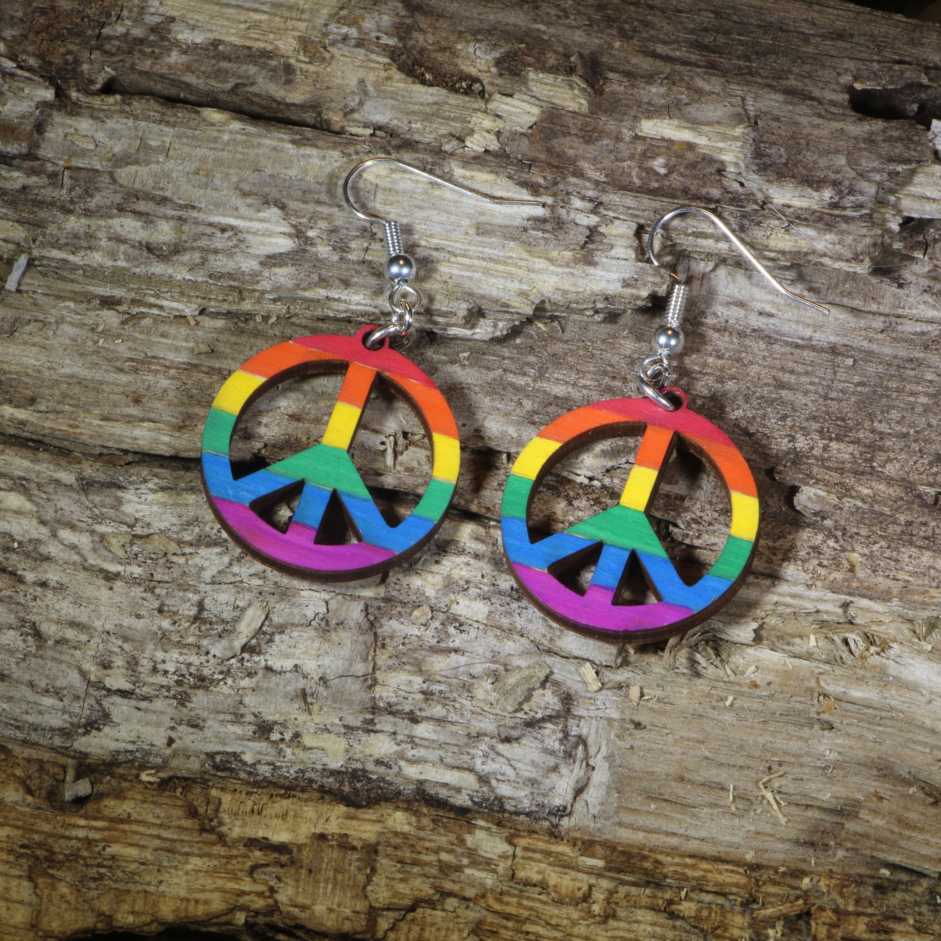 Hand-painted wooden rainbow peace sign dangle earrings featuring a colorful peace symbol design, hypoallergenic sterling silver hooks, and lightweight LGBTQ+ pride jewelry for peace lovers, festival outfits, and rainbow accessory fans by Cate&