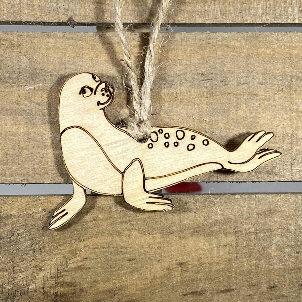 Hand-painted wooden sea lion Christmas ornament featuring a playful coastal animal design with smooth curved body and flippers, unique holiday decor for ocean lovers and marine life enthusiasts by Cate’s Concepts