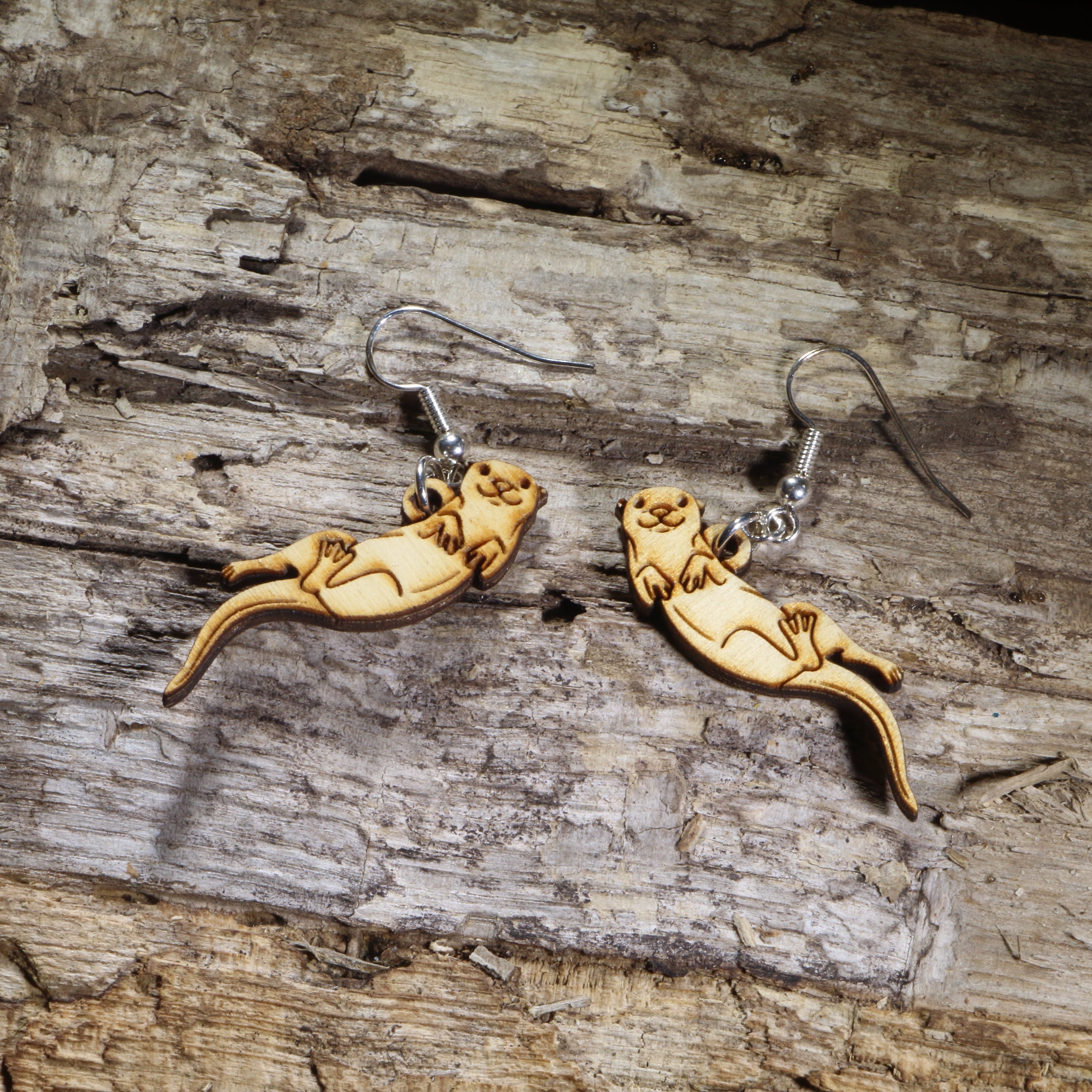 Hand-painted wooden sea otter dangle earrings on hypoallergenic .925 sterling silver hooks. Lightweight ocean wildlife jewelry for sea otter lovers, marine life enthusiasts, coastal adventurers, and animal lovers.
