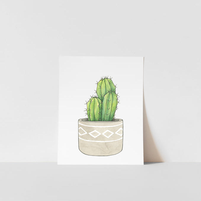 A tall cactus print with a beige background, featuring a simple illustration of a cactus in a pot, signed by artist Heather S Vitticore.
