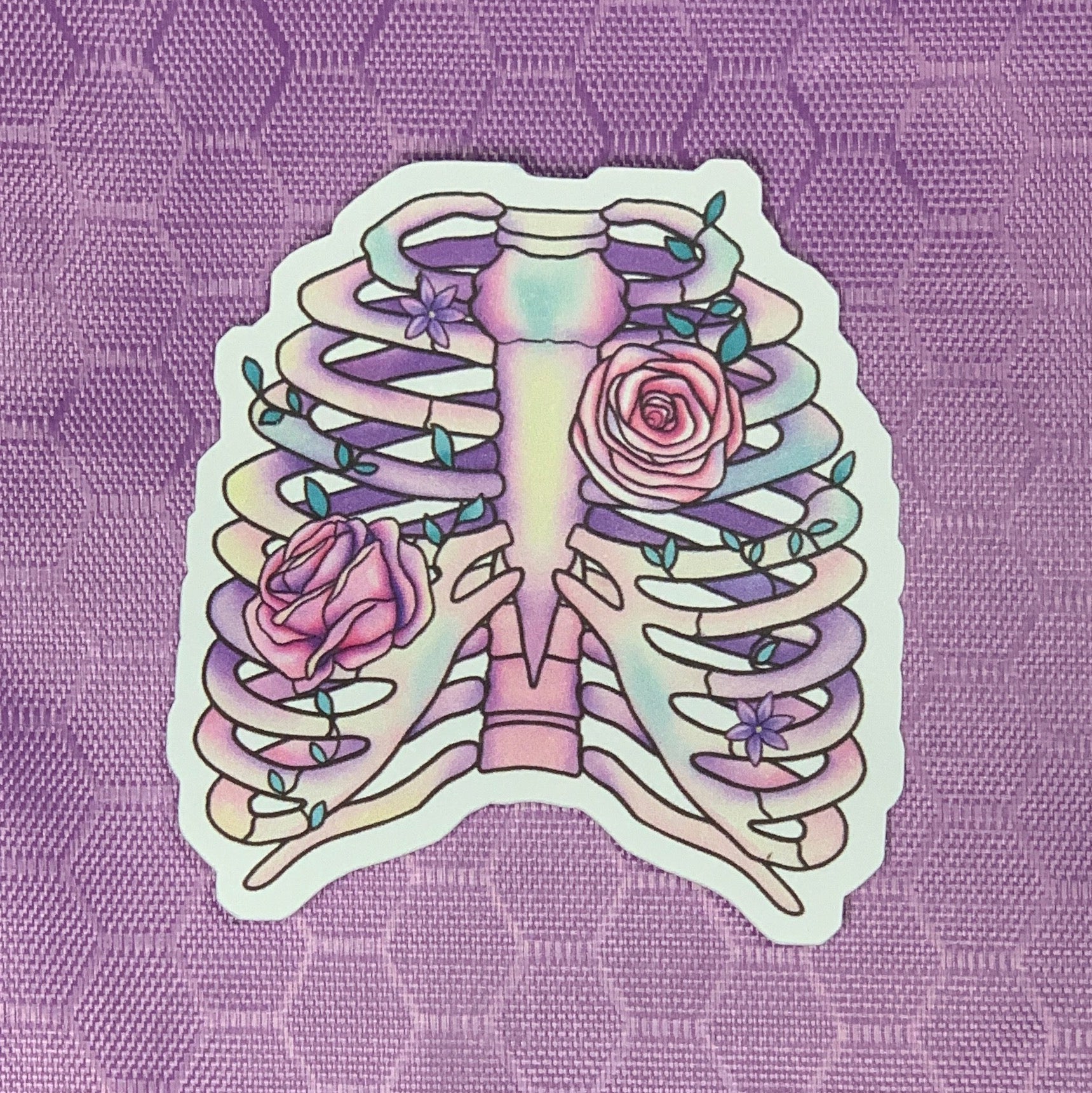 Our dreamy and whimsical die cut skeletal remains sticker features a softly pastel shaded ribcage with vined pink roses winding around the bones. 