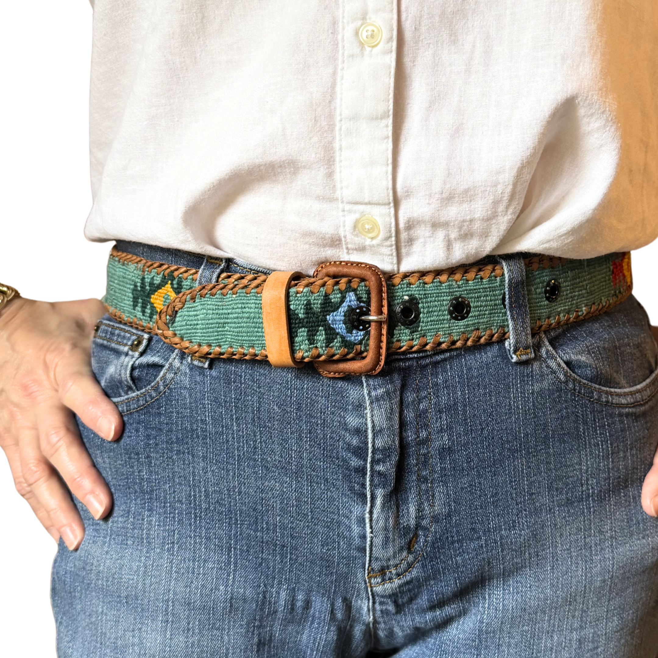 Person wearing a colorful belt with a white shirt and blue jeans.