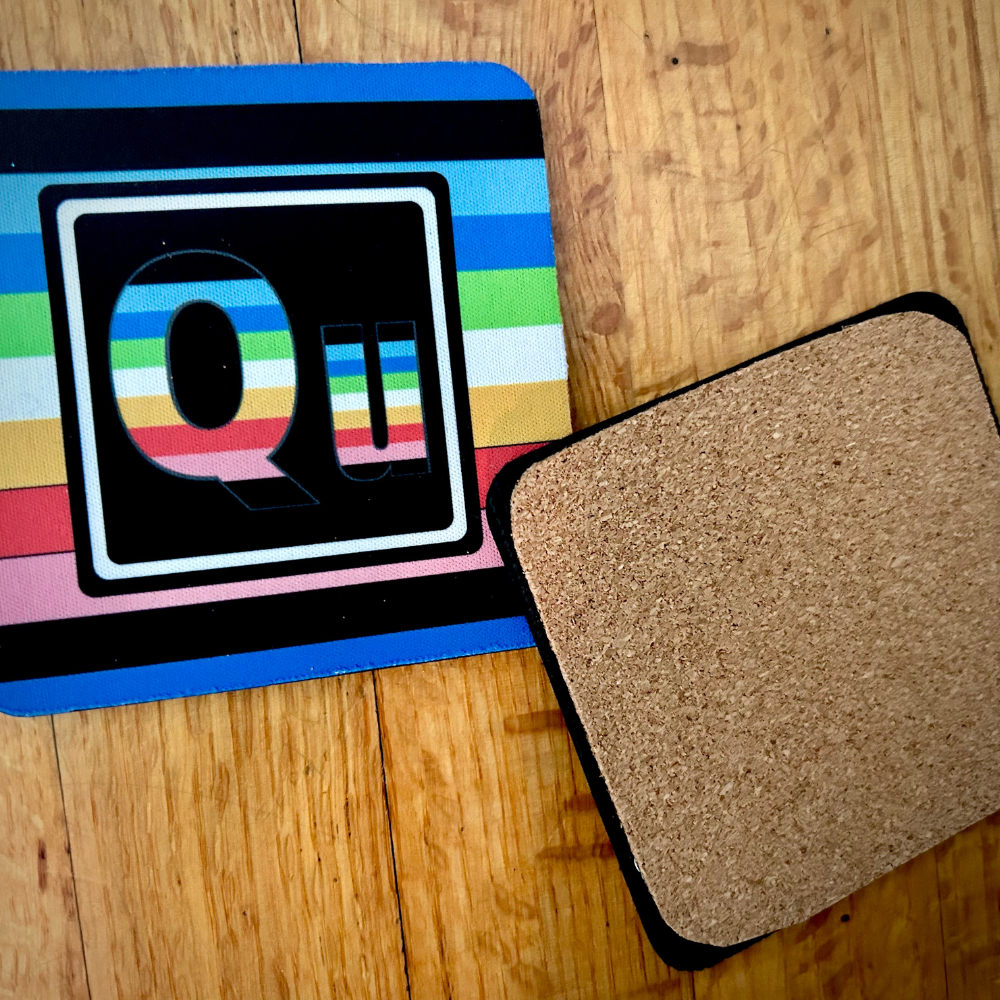 The Queer Element coaster. On the left is the front of the Queer element with the colors of the Queer flag. On the right is te back of our coasters, which have cork across the back of the coaster.