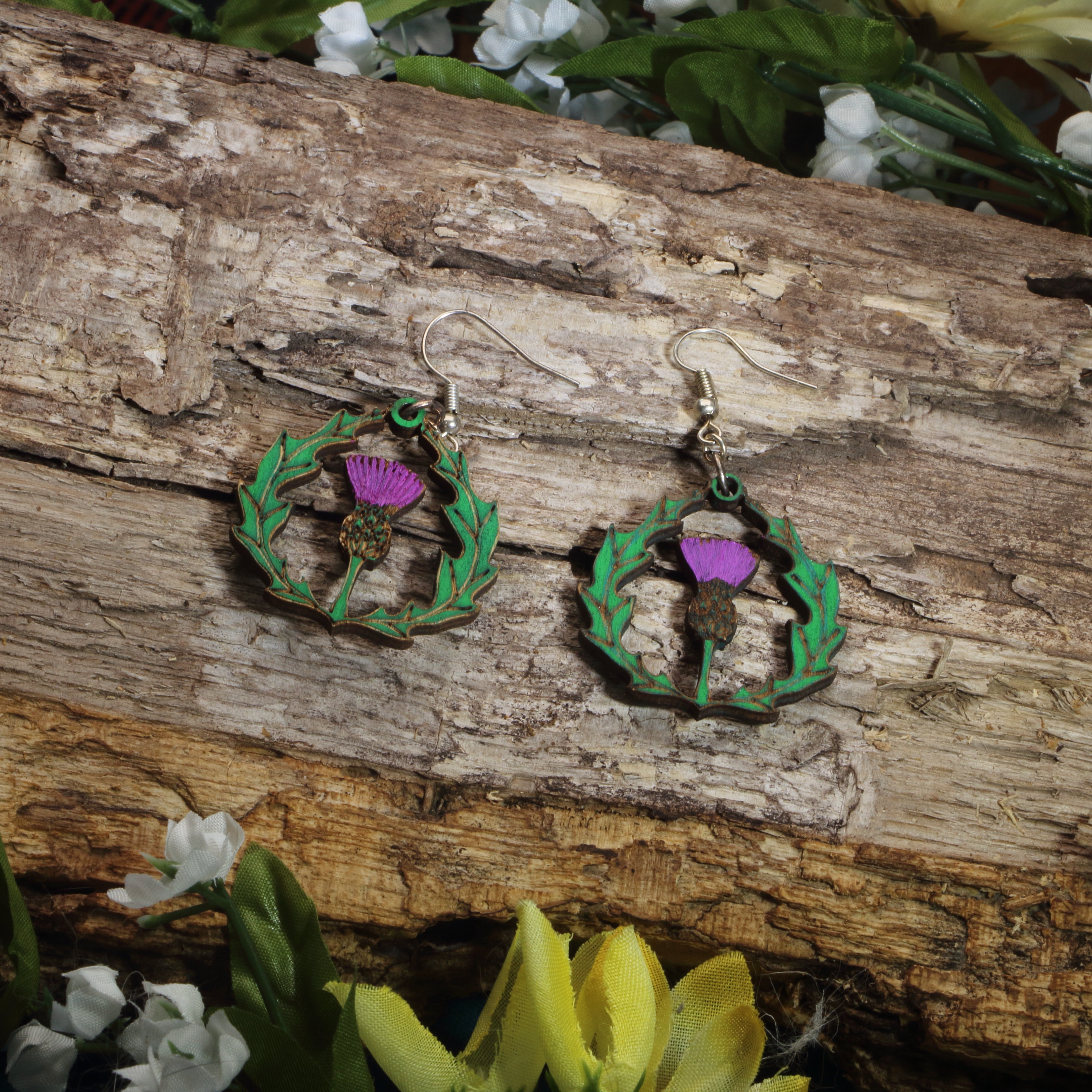 Hand-painted wooden thistle dangle earrings featuring a purple Scottish thistle framed by Celtic-inspired greenery, hypoallergenic sterling silver hooks, and lightweight heritage jewelry for Scottish pride, Celtic culture, and nature lovers by Cate’s Concepts