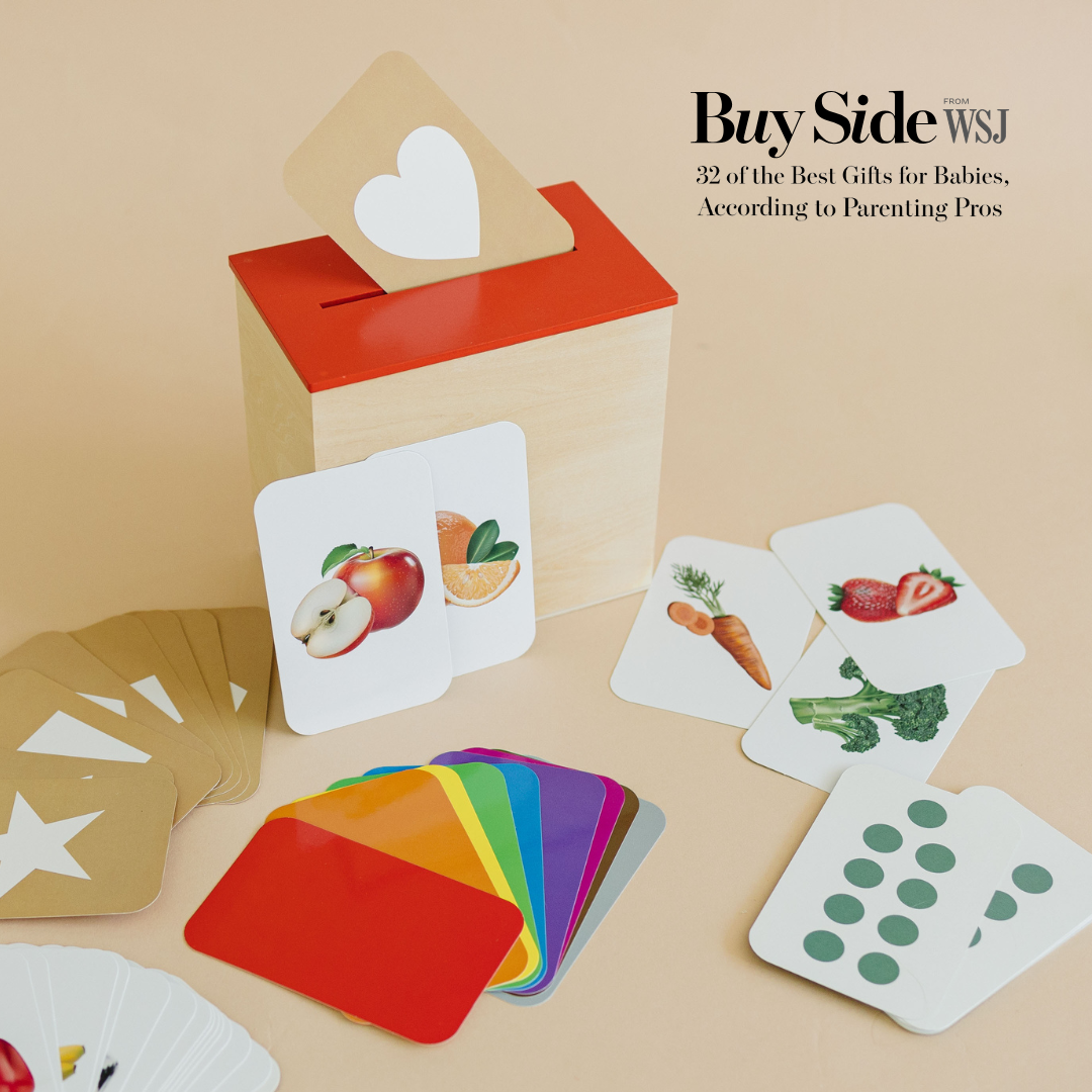 Wooden box and colorful educational flashcards with images of fruits, vegetables, and shapes on a beige background.