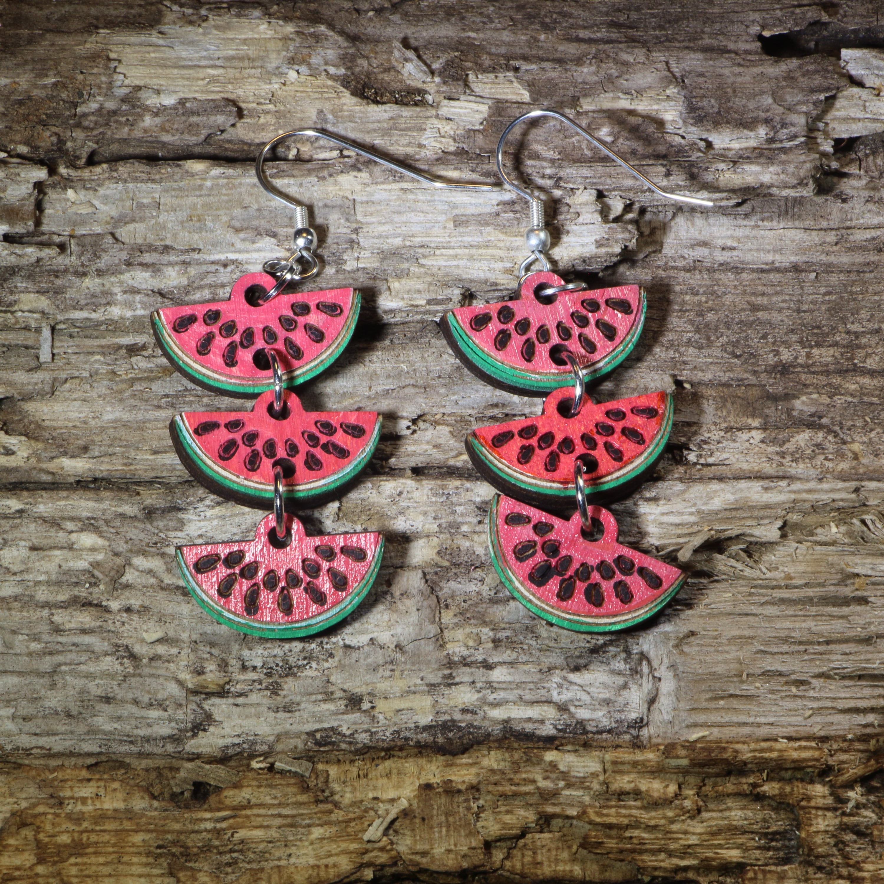 Hand-painted wooden watermelon slice cascade dangle earrings featuring layered juicy watermelon wedges with vibrant red, green, and black seed details. Crafted from lightweight wood with hypoallergenic .925 sterling silver hooks, these eye-catching earrings are perfect for summer fashion, fruit lovers, beach vacations, farmers markets, picnics, and anyone who enjoys bold food-inspired statement jewelry.