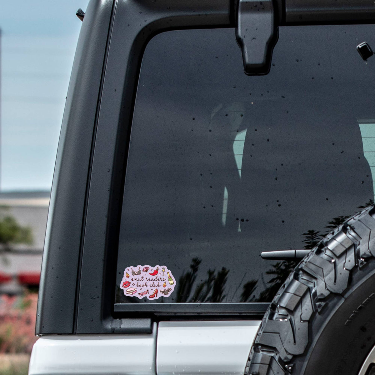 Car window with a sticker and tire visible outdoors
