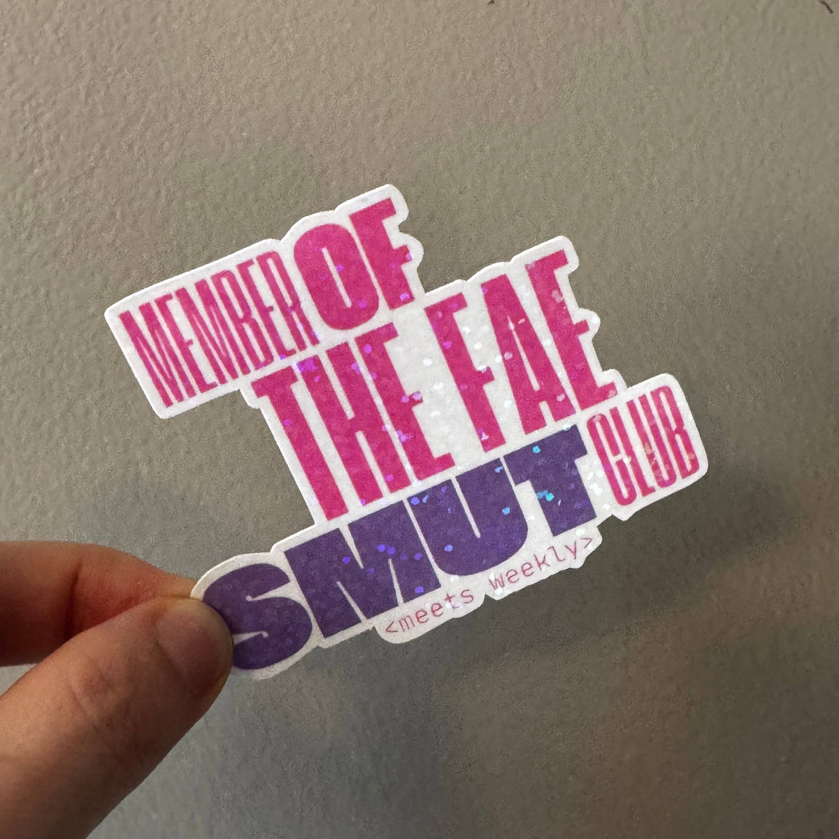 A hand holding a die-cut sticker that reads &