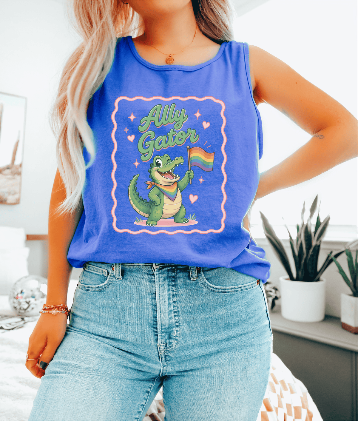 Person wearing a blue tank top with a graphic of a crocodile holding a rainbow flag and the text &