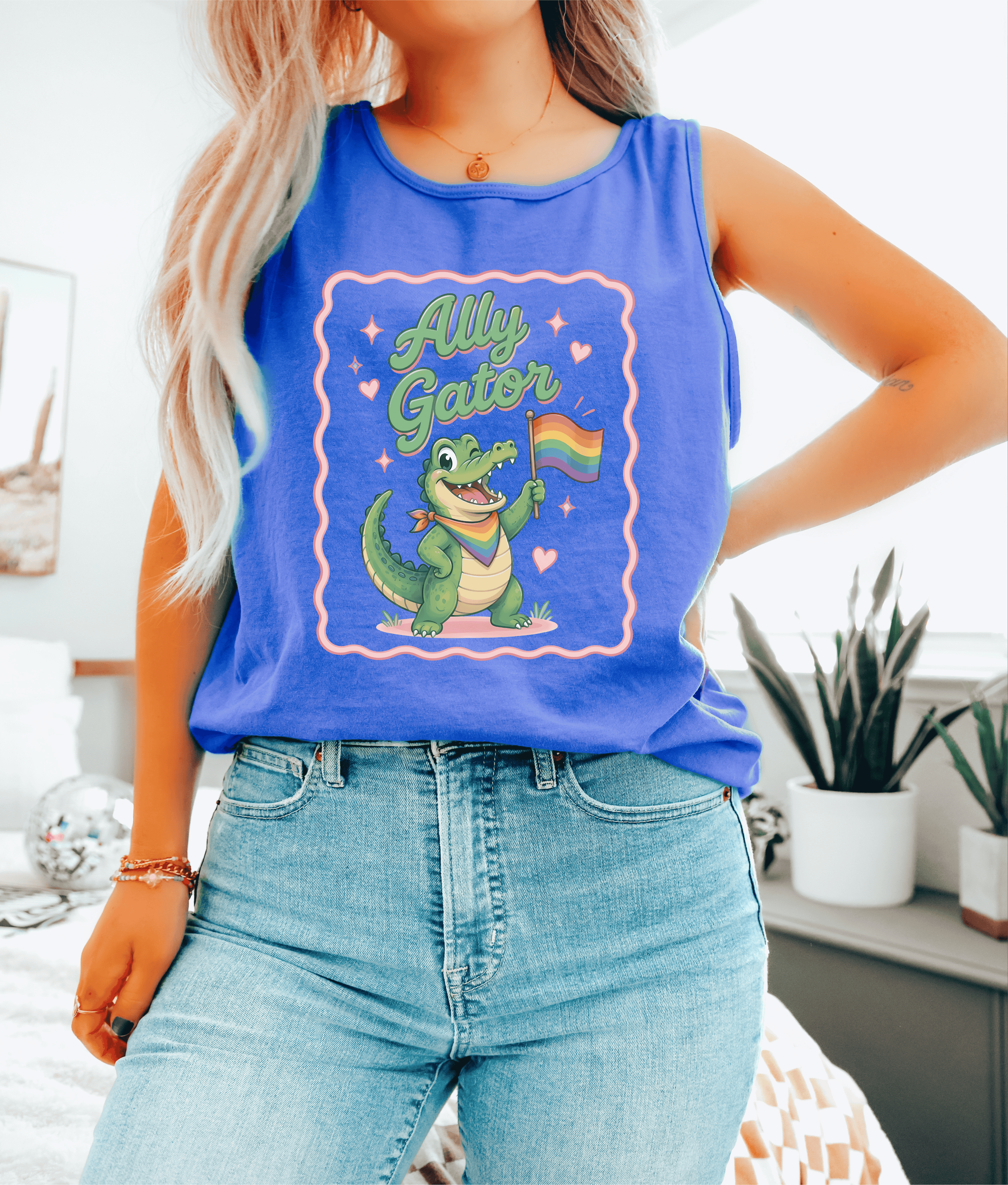 Person wearing a blue tank top with a graphic of a crocodile holding a rainbow flag and the text &