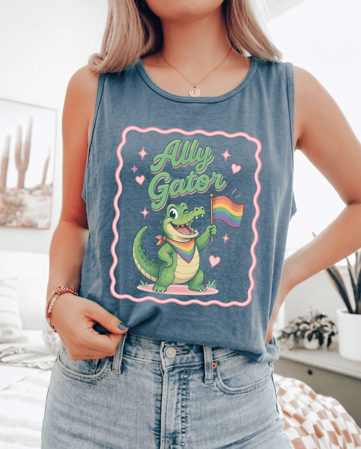 Person wearing a tank top with a cartoon gator holding a rainbow flag and &
