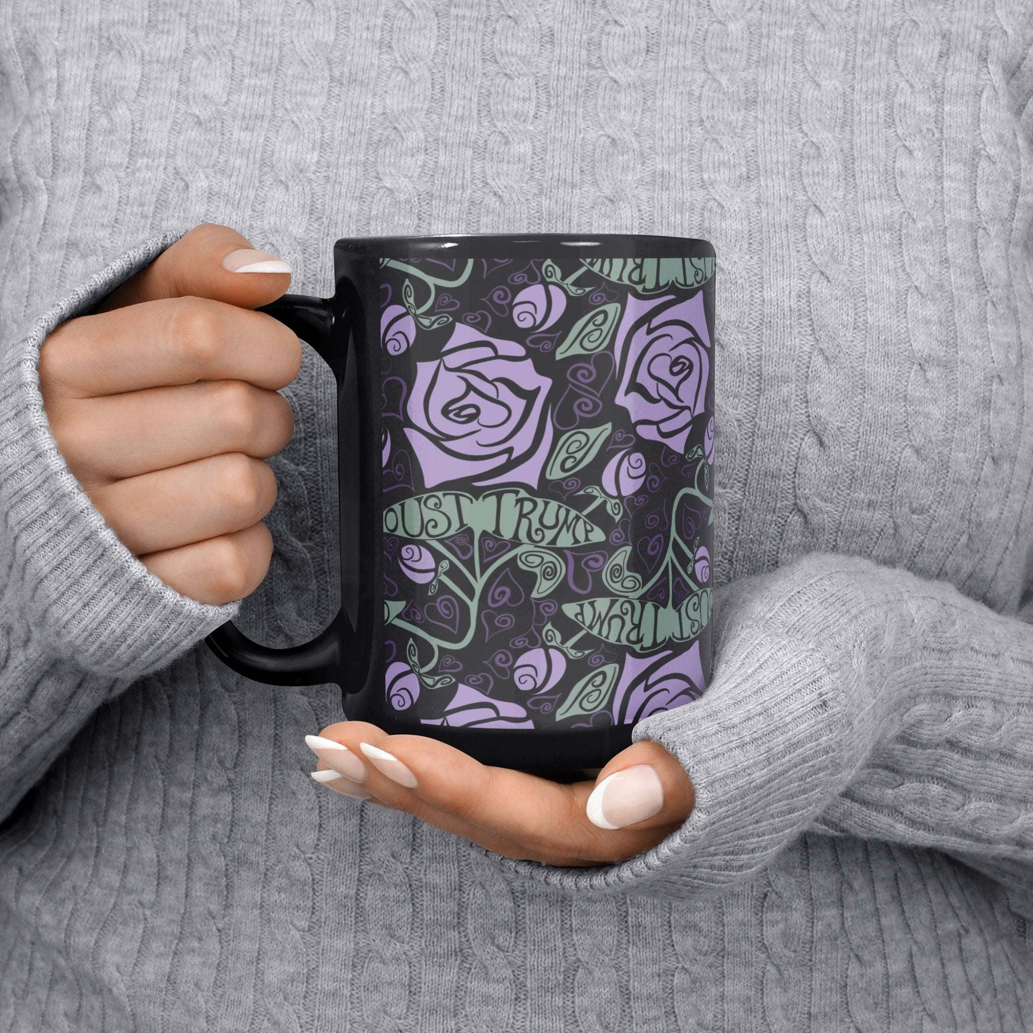 Person in grey cable knit sweater holding 15 oz anti-Trump floral gothic coffee mug