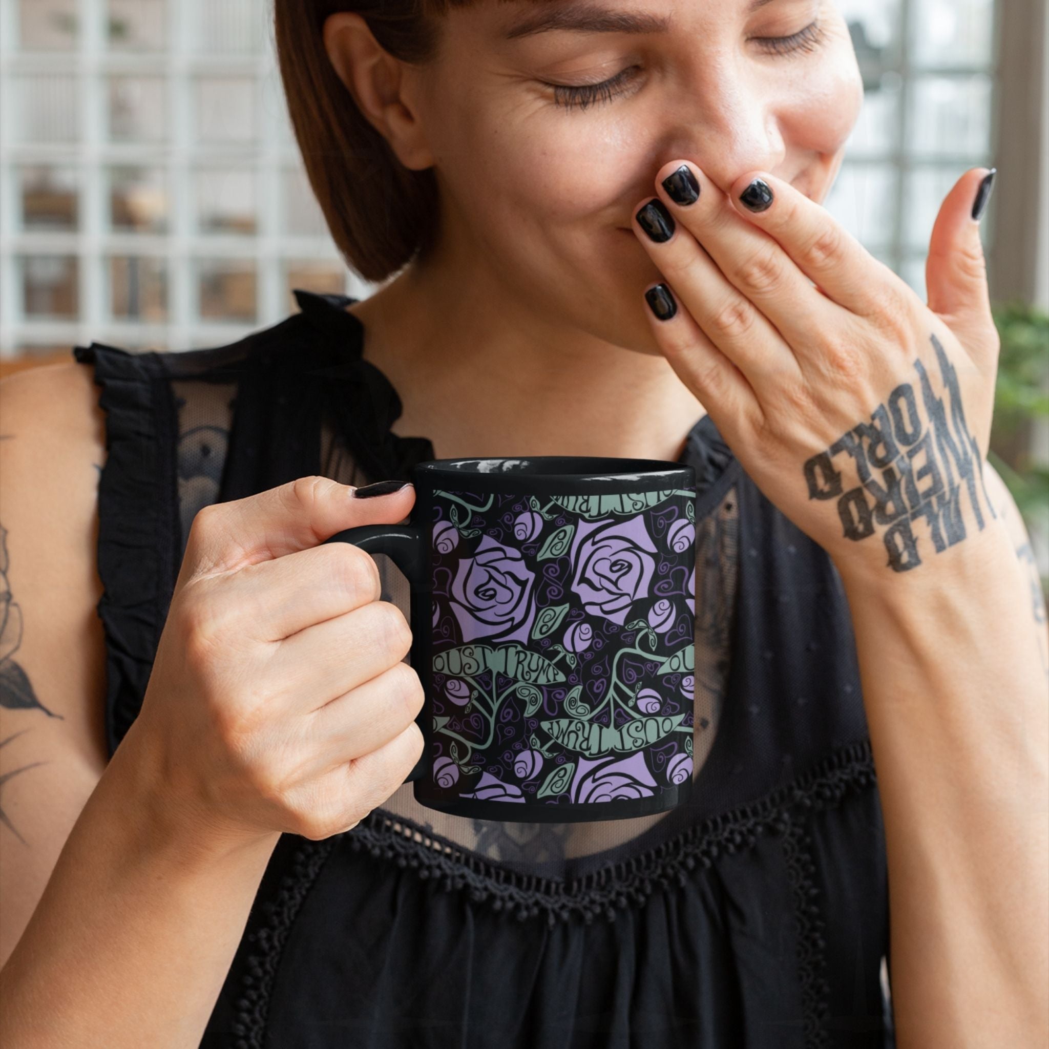 Tattooed woman laughing while holding anti-Trump dark floral gothic coffee mug