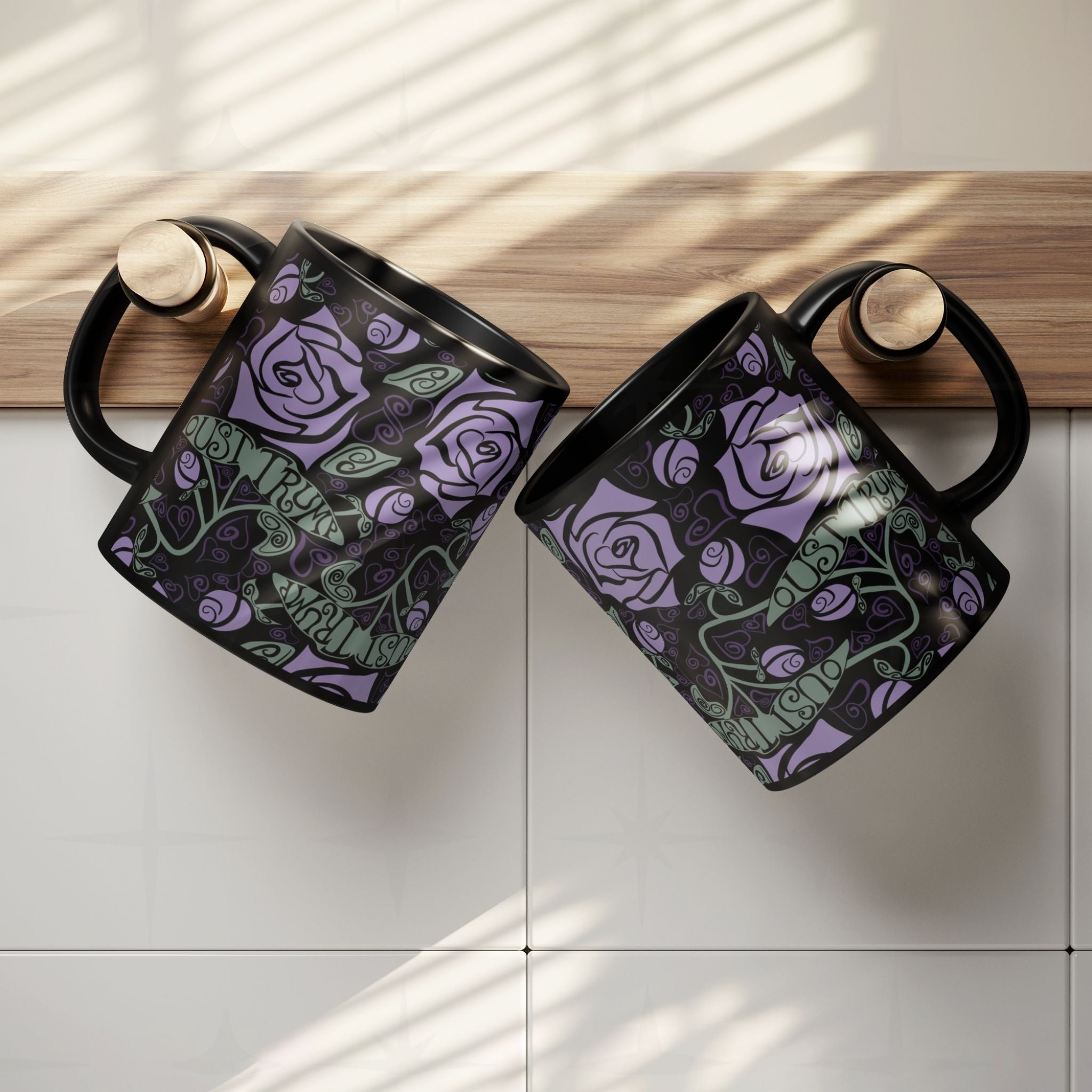 Two anti-Trump hidden message mugs with gothic rose botanical print hanging on kitchen cabinet edge