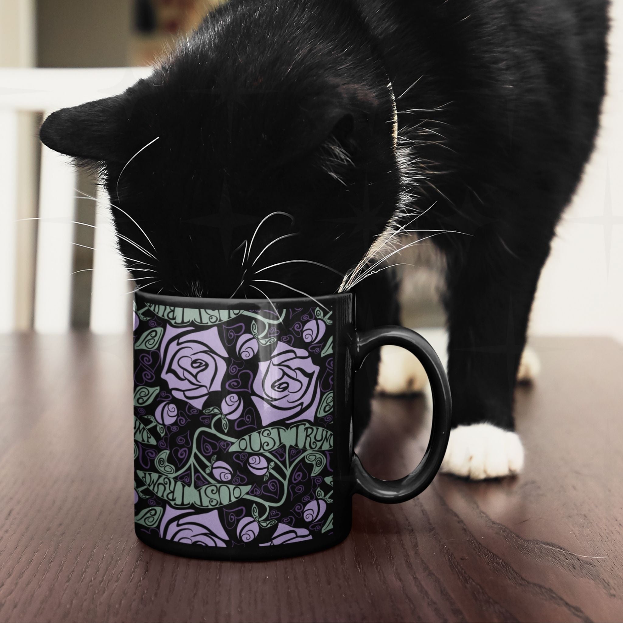 Black cat inspecting anti-Trump hidden message mug with lavender rose botanical wrap print on wooden surface