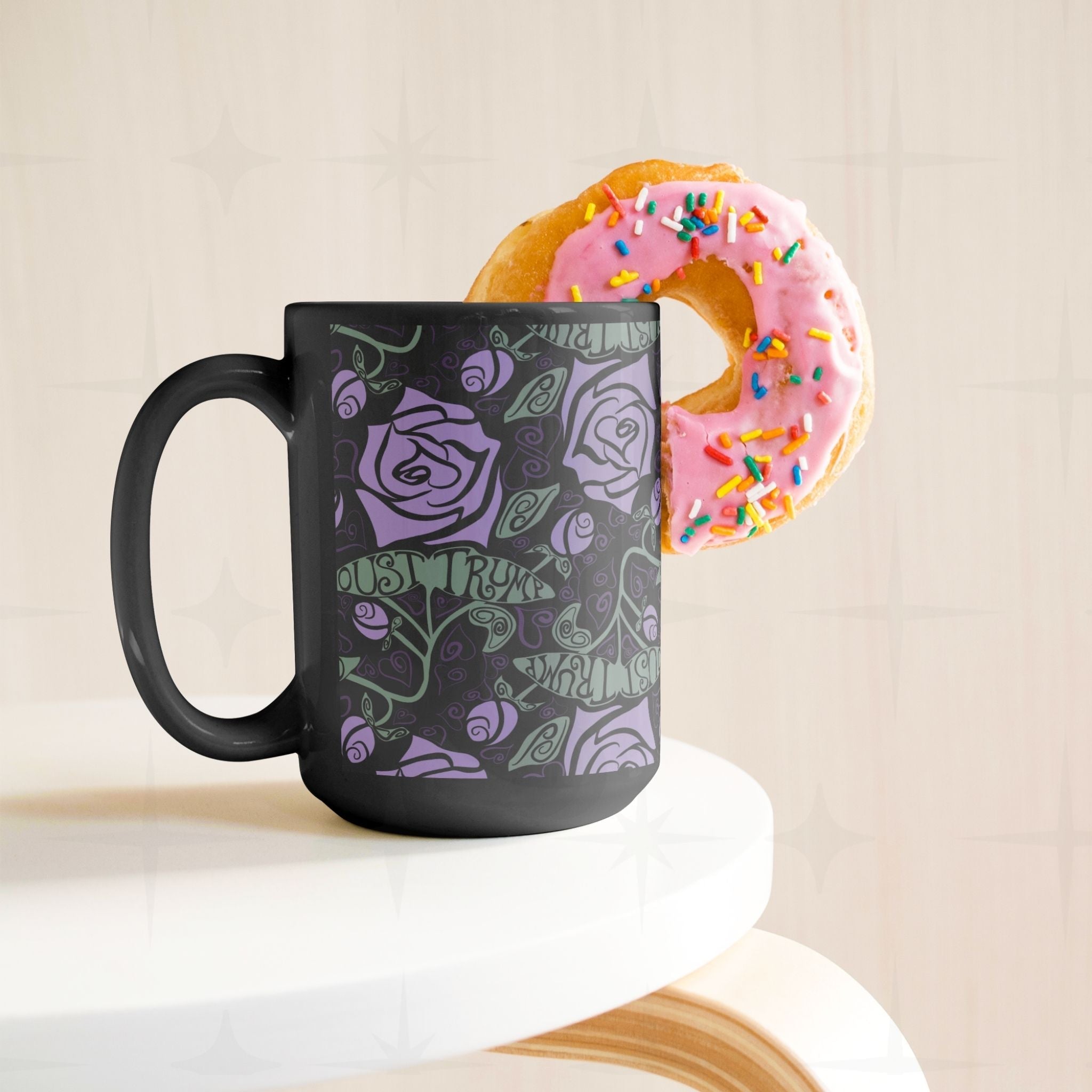 15 oz anti-Trump black ceramic mug with lavender floral print displayed on white cake stand with sprinkle donut