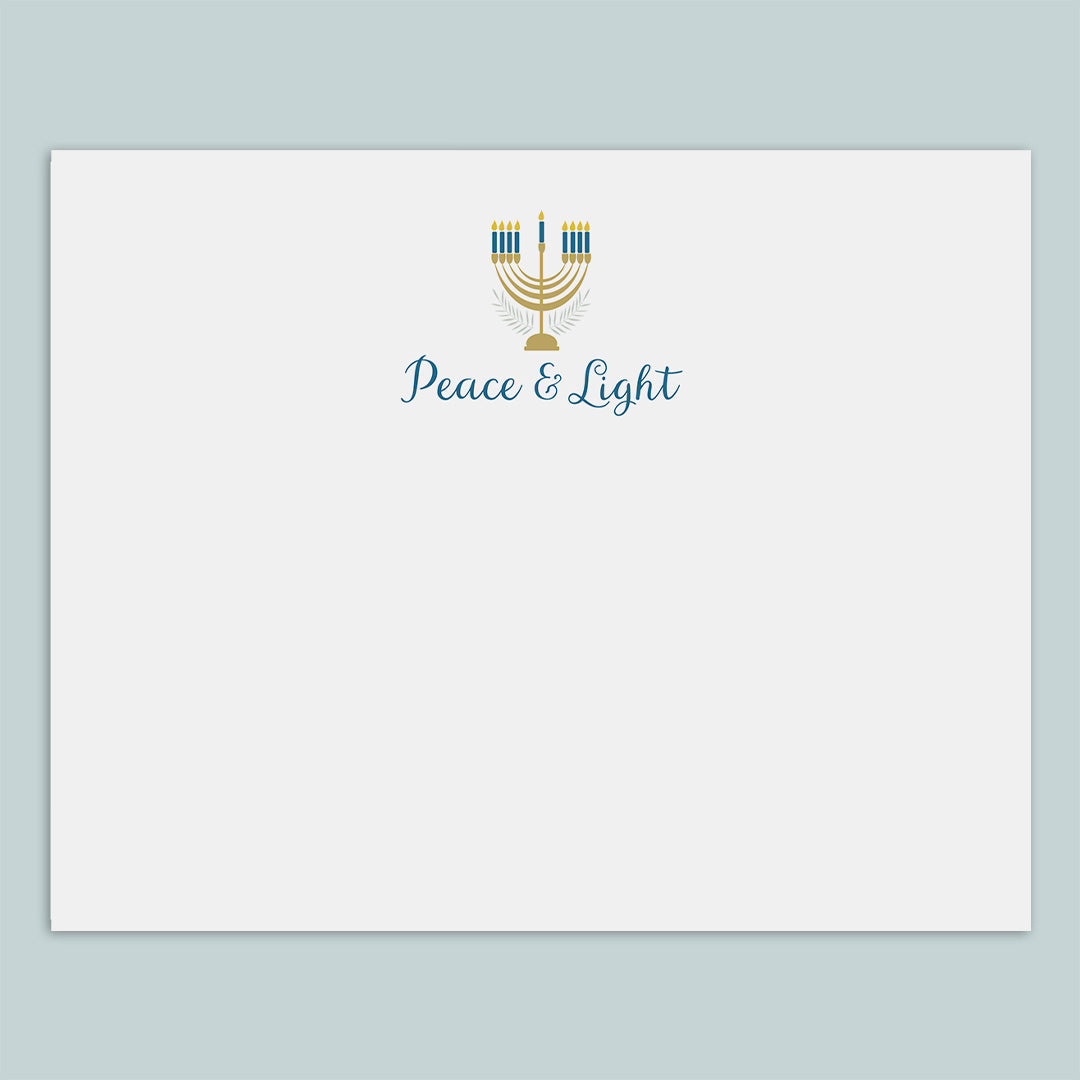 A white envelope with a graphic design featuring a menorah and the text "Peace & Light" printed on it.