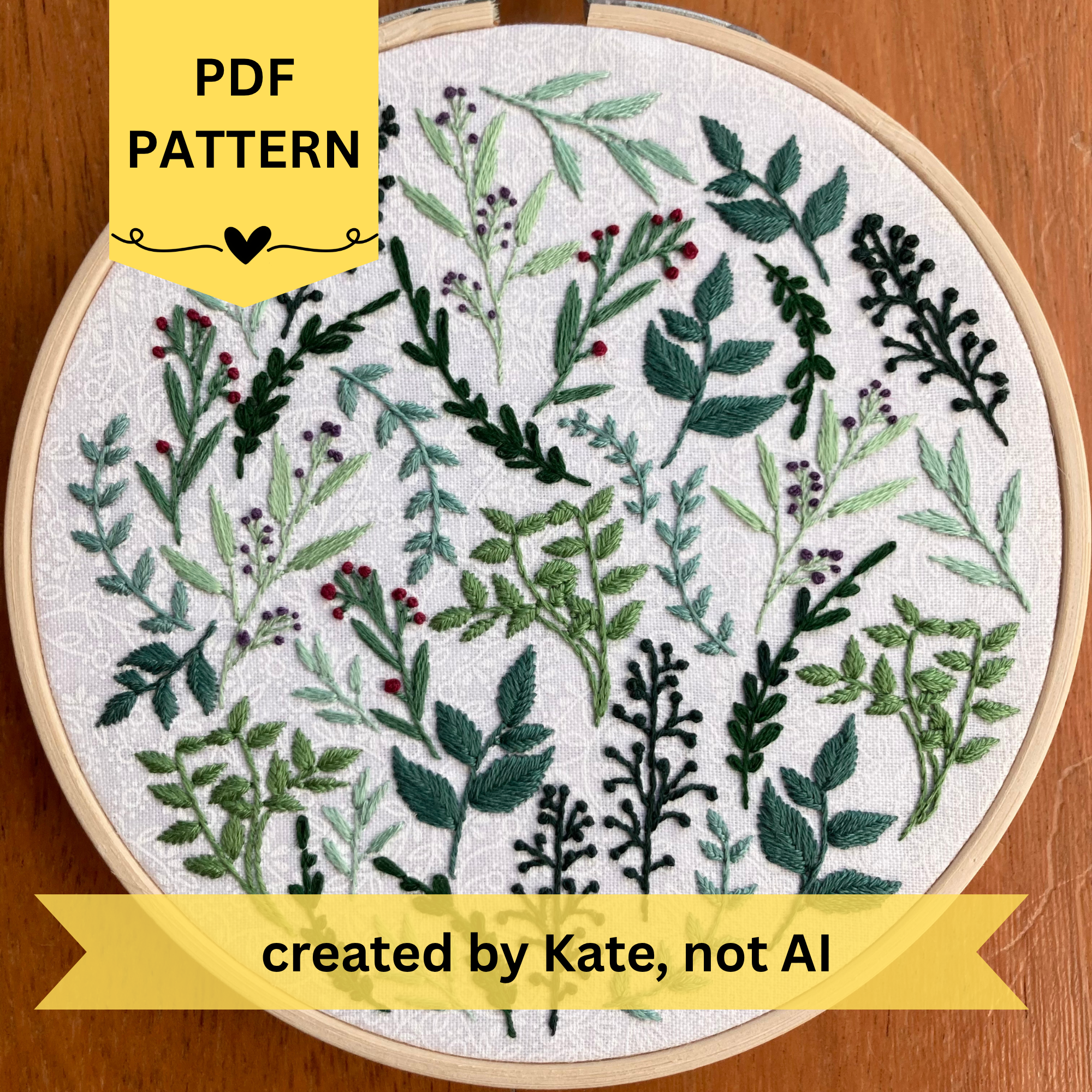 PDF Pattern created by Kate, not AI. 8 different botanicals hand embroidered in a scattered pattern on white cotton fabric. There is a range of yellow green and blue green leaves and stems, as well as red and purple flower buds. This wall art is framed in a light wood embroidery frame.