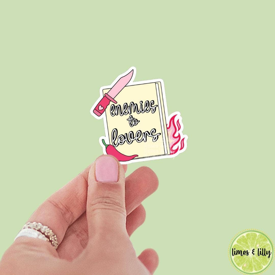 Hand holding a sticker with text and graphics on a light green background