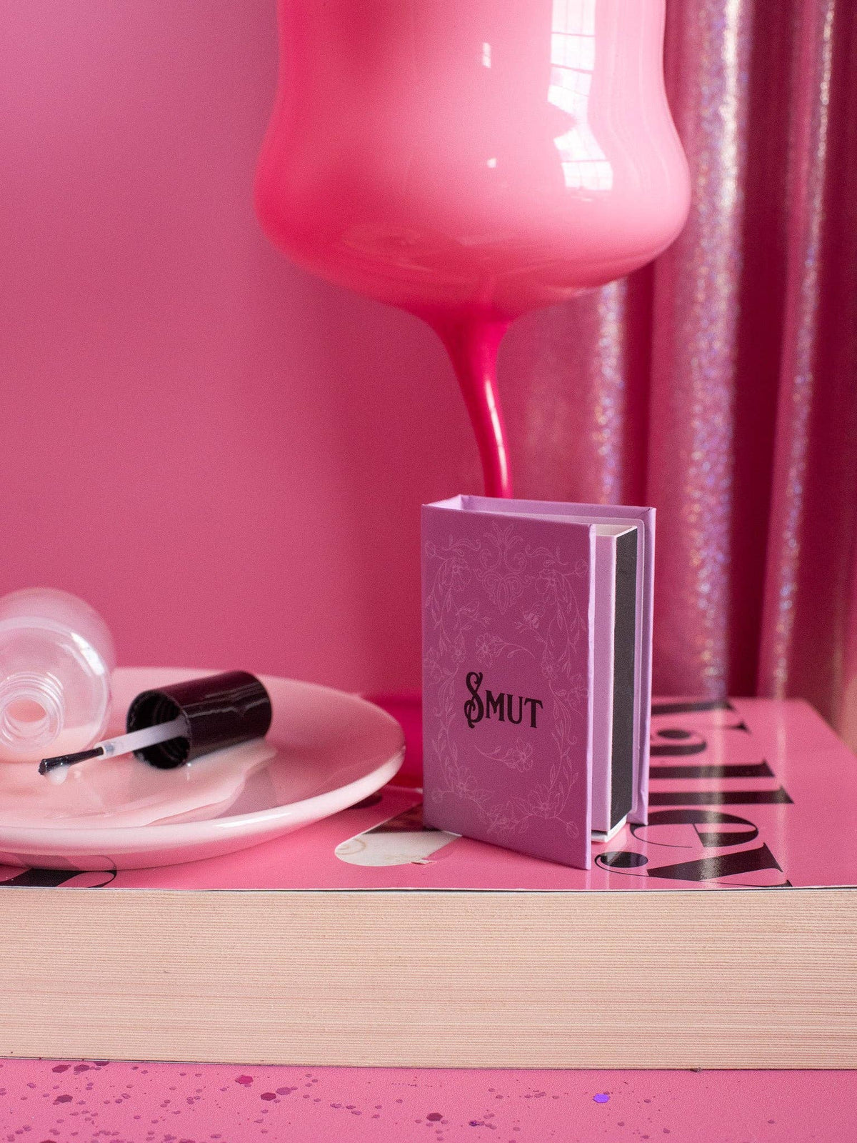 Pink bottle, nail polish, and book titled &