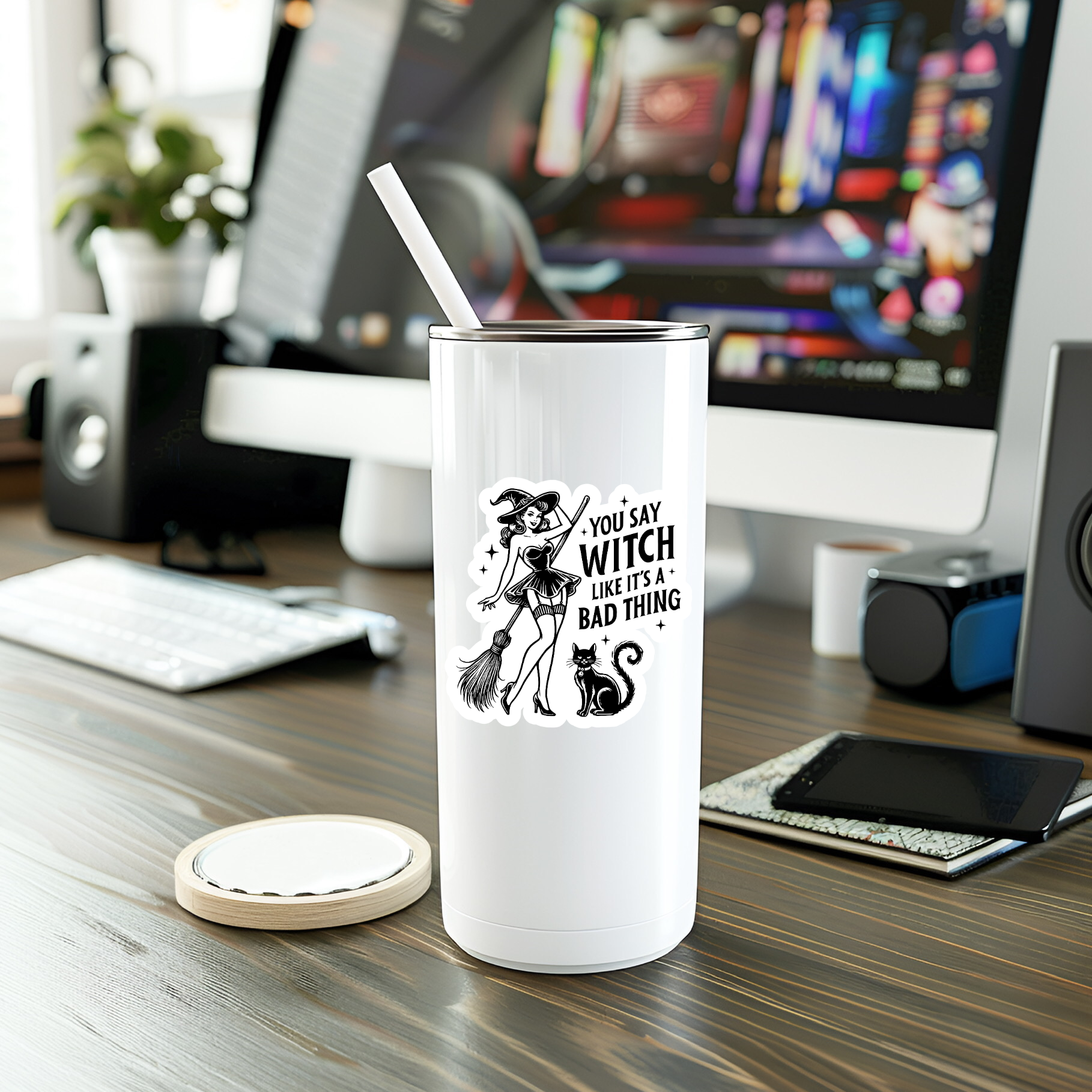 White tumbler with a graphic design on a desk with a computer in the background
