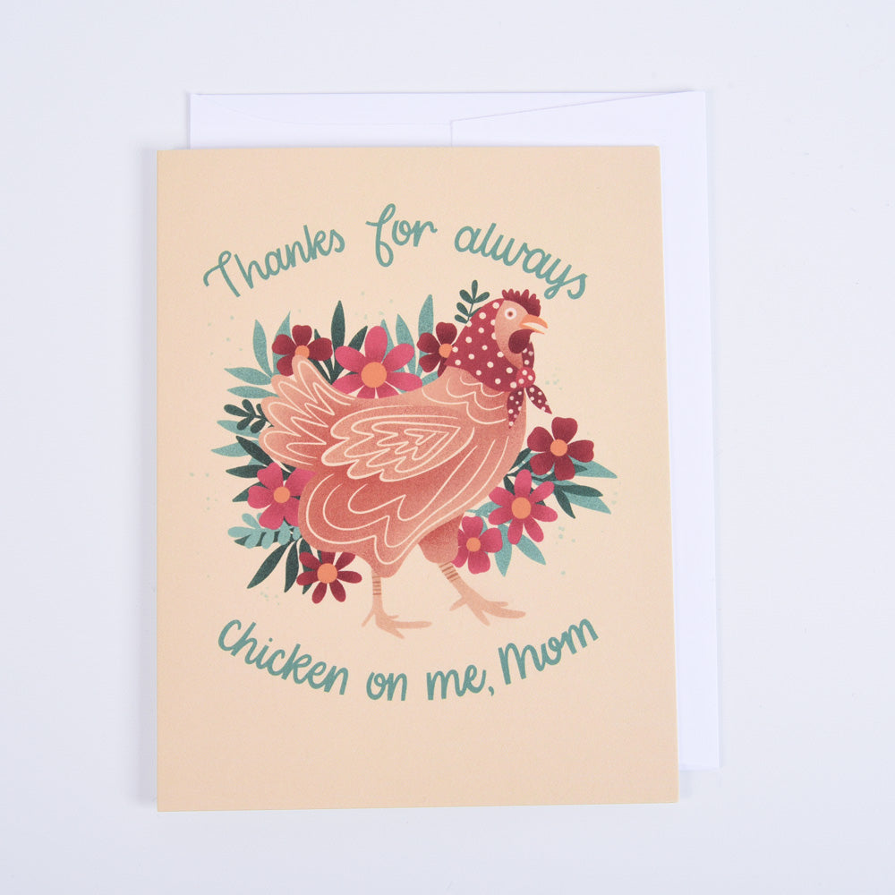 A greeting card with a colorful illustration of a chicken surrounded by flowers with a message "thanks for chicken on me, mom"