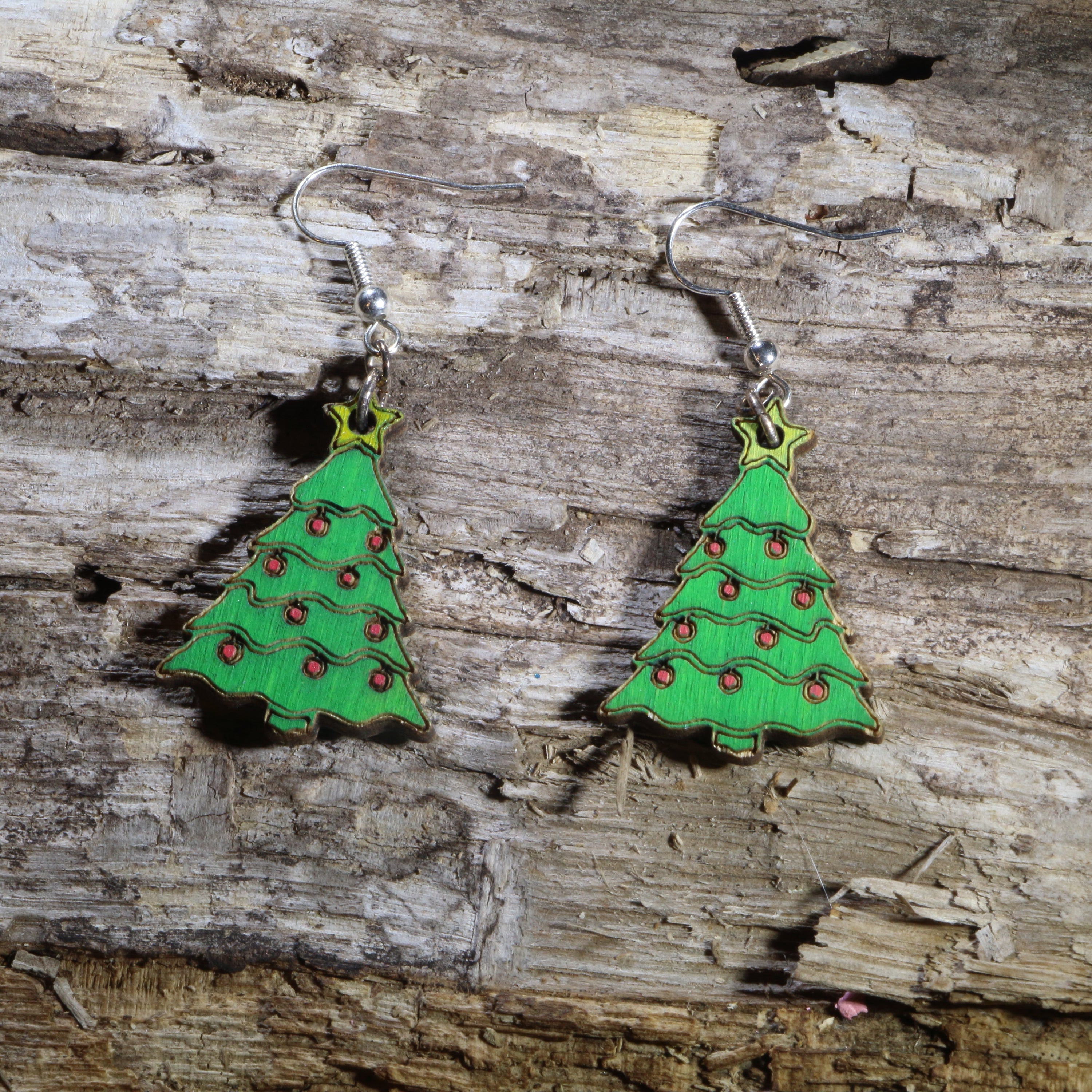 Hand-painted wooden Christmas tree dangle earrings featuring a festive evergreen tree decorated with colorful ornaments, garland, and a bright star topper. Crafted from lightweight wood with hypoallergenic .925 sterling silver hooks, these cheerful holiday earrings are perfect for Christmas parties, winter celebrations, holiday markets, festive outfits, Christmas gift giving, and anyone who loves seasonal jewelry.