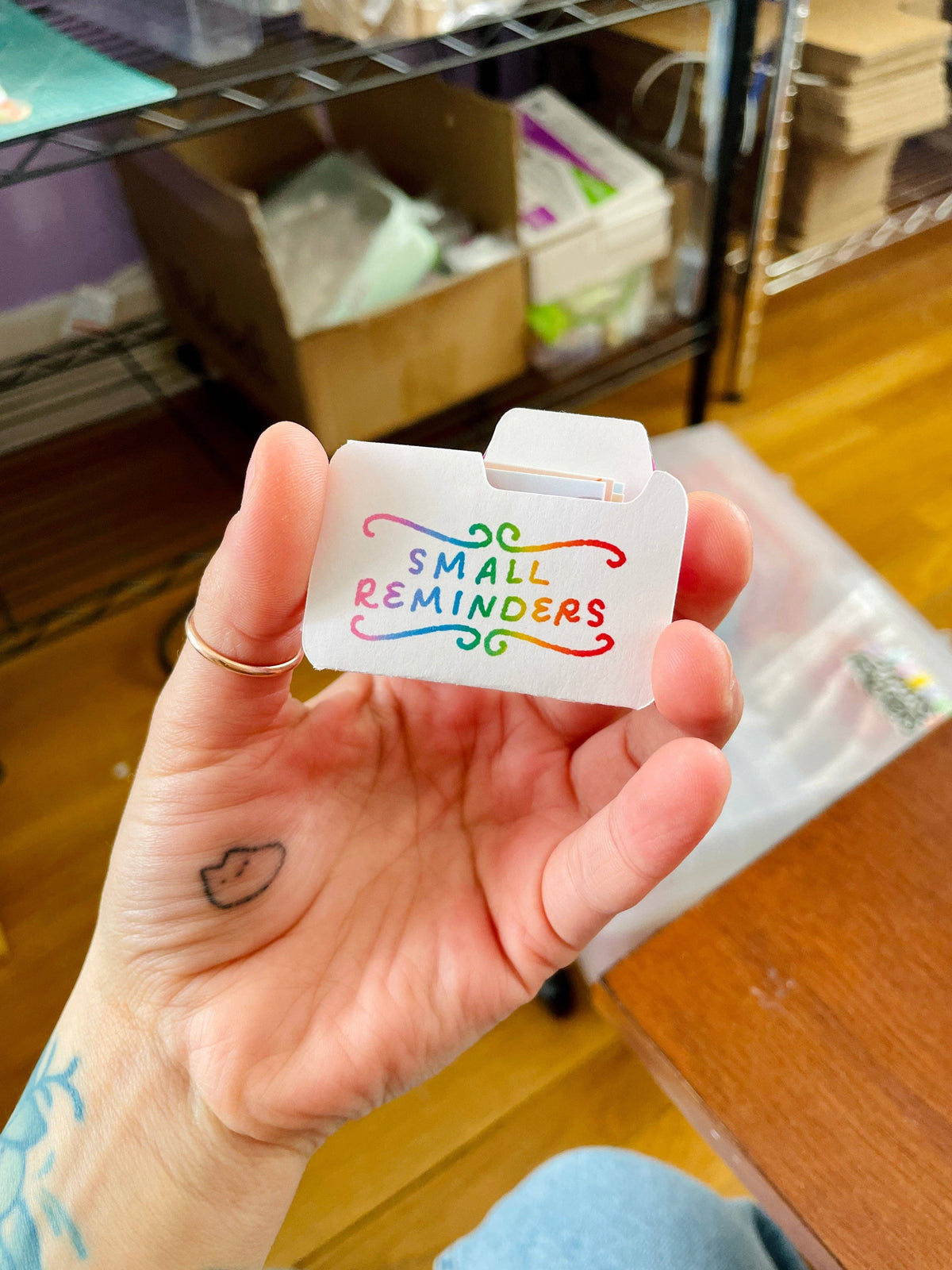 Hand holding a small white card with colorful text &