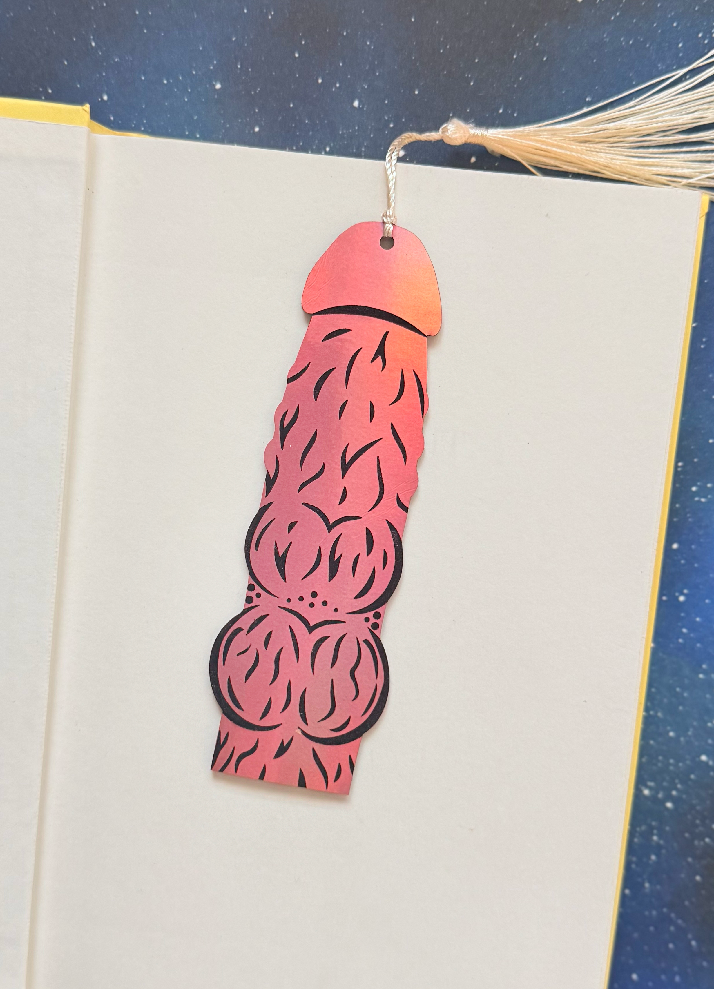 Decorative pink and orange bookmark with cut-out design on a book page.