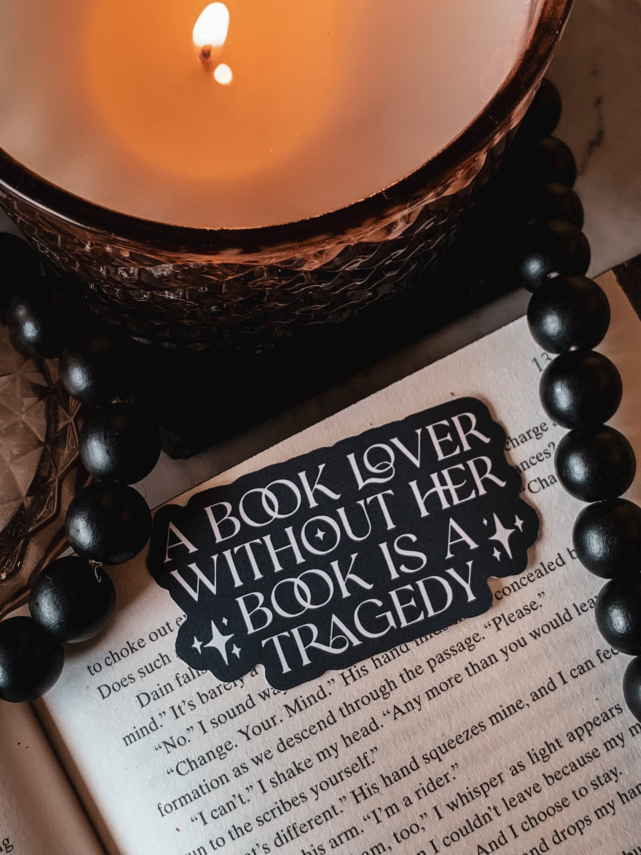 Candle, beads, and a book with a decorative tag on an open book