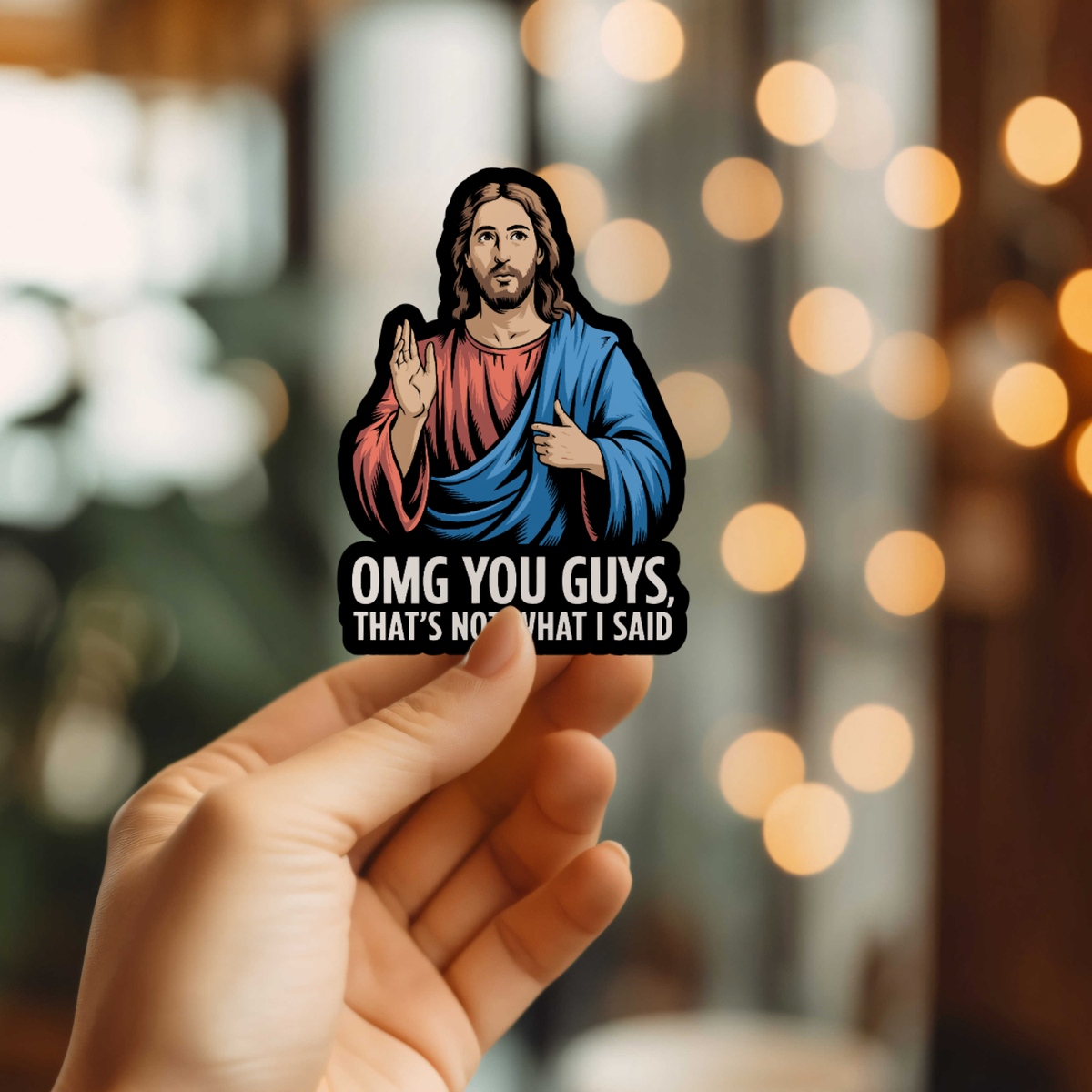 Sticker of a religious figure with text held by a hand against a blurred bokeh background