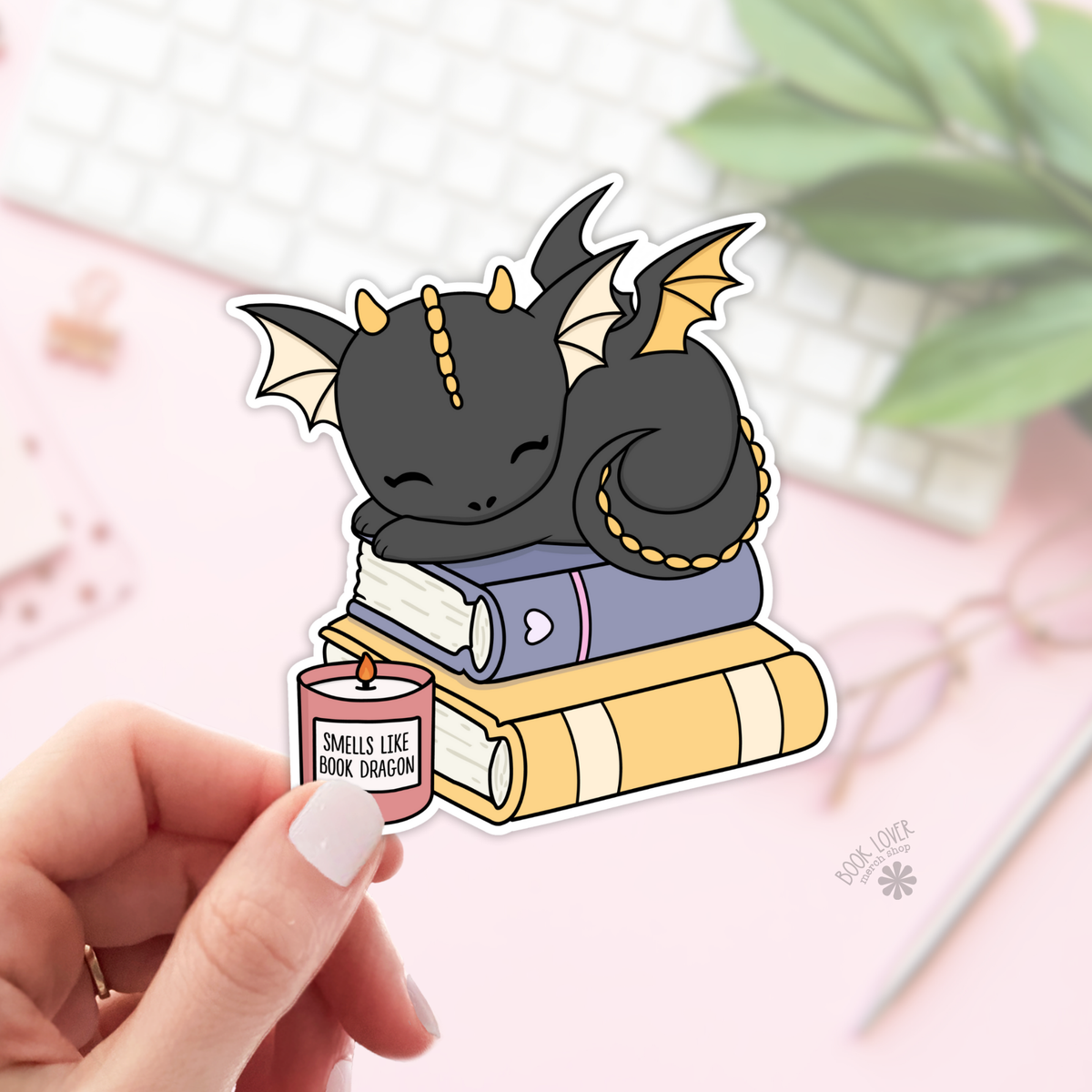 Sticker of a dragon sitting on books with a candle labeled &