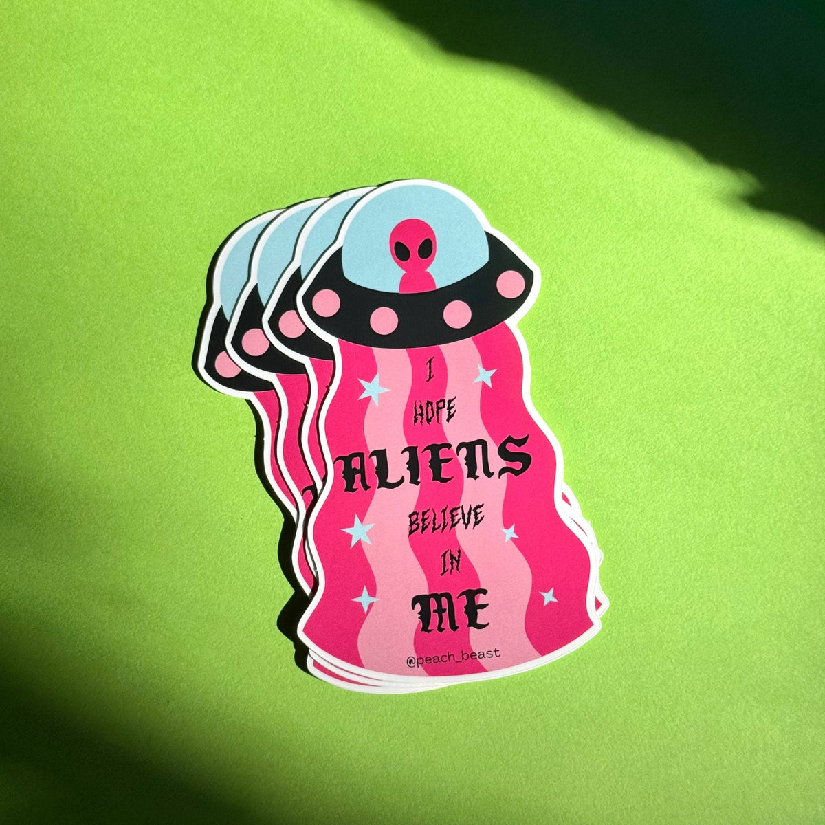 Sticker with alien design and text on a green background