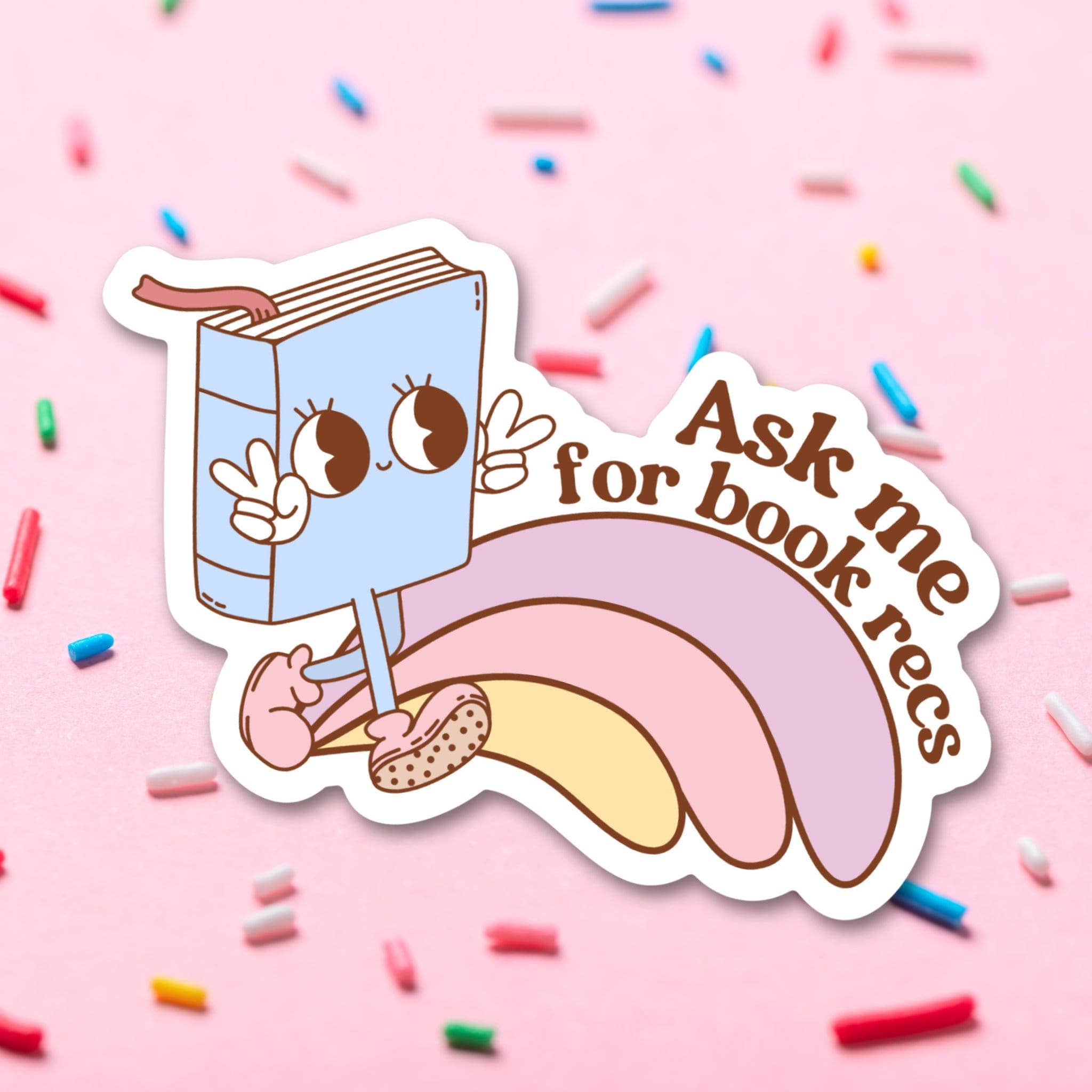 Sticker with a cartoon book character on a pink background with sprinkles.