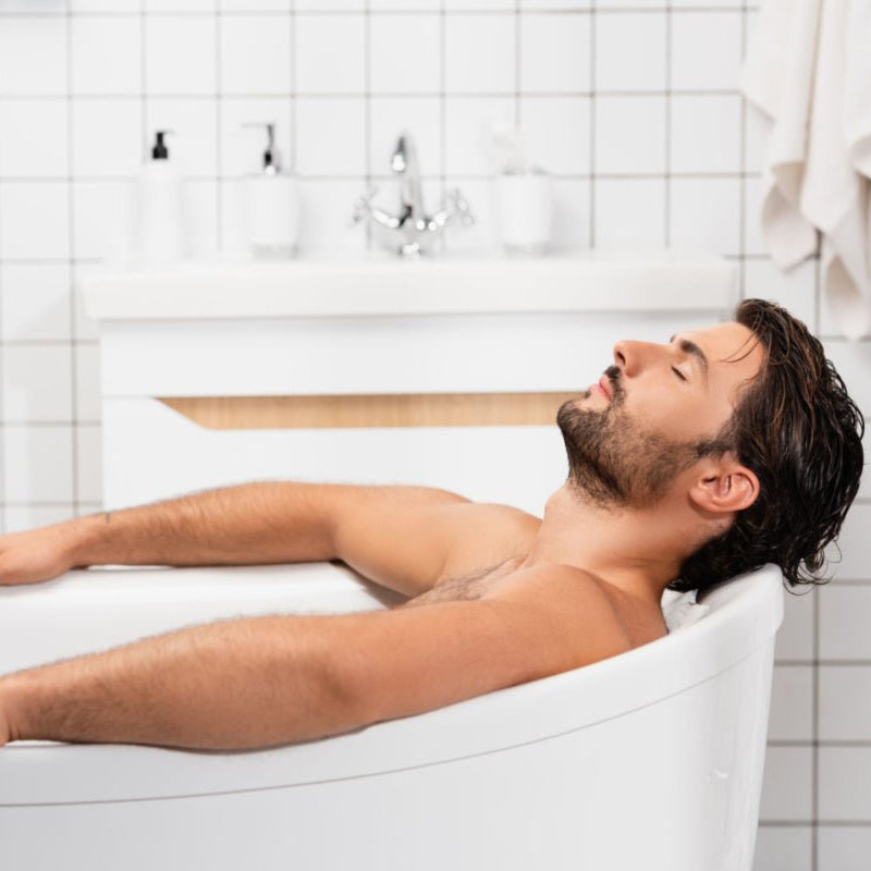 Man relaxing in a tub using Elixir Mind Body Botanicals Mineral Soaking Salts from Elixir Mind Body Boutique
