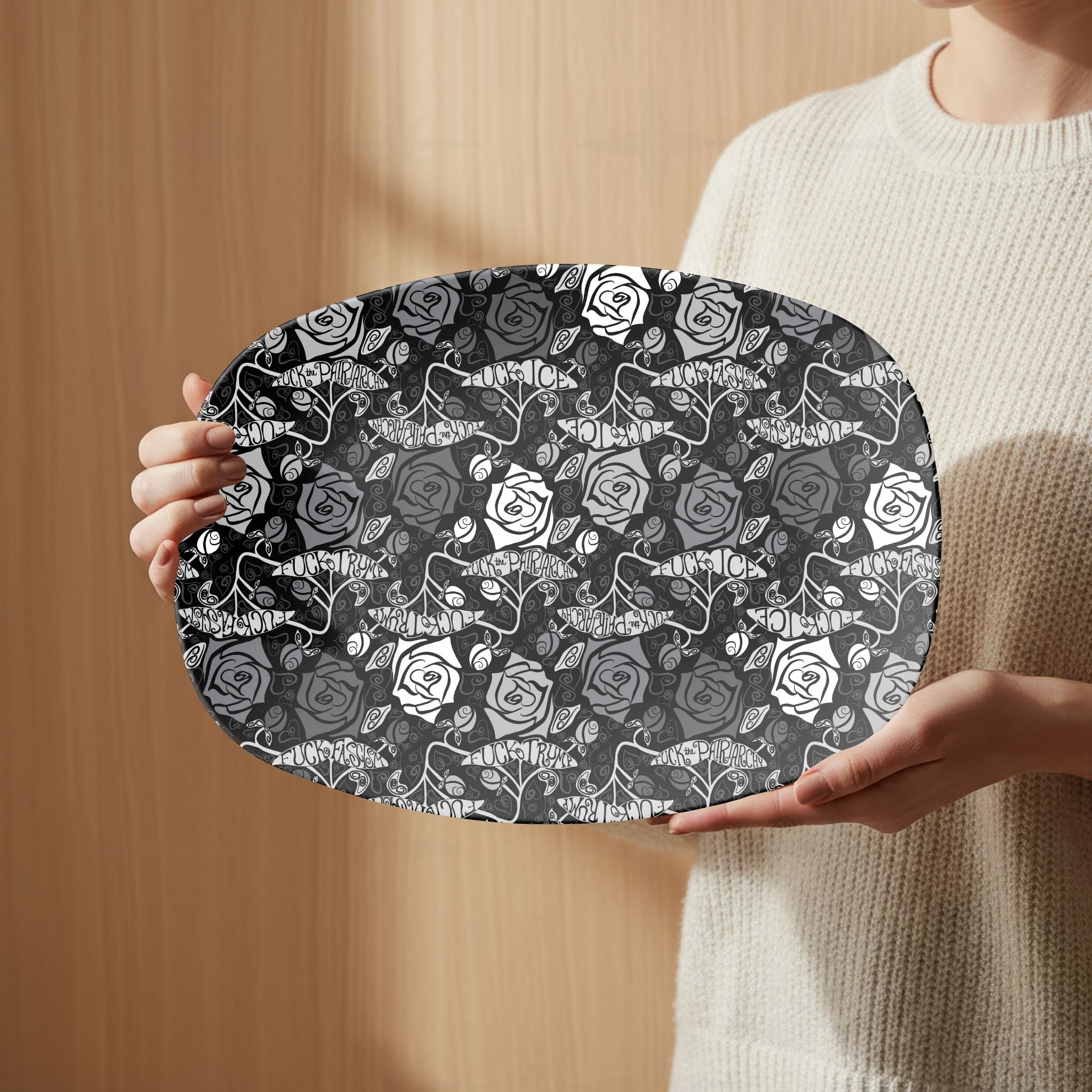 Person in cream sweater holding feminist hidden profanity gothic rose serving platter against warm wood background