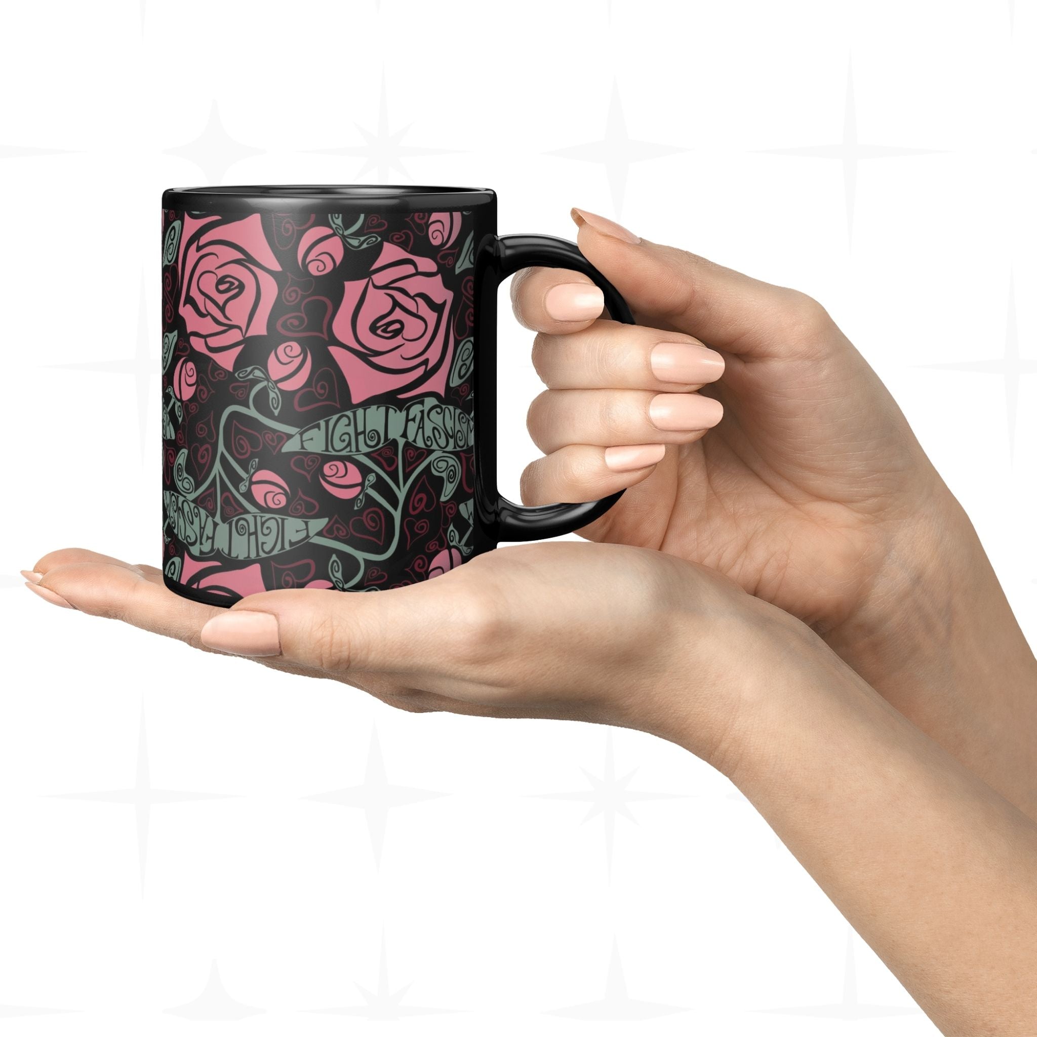 One hand holding the 11oz Fight Fascism black ceramic mug from below showing full Art Nouveau rose wrap print