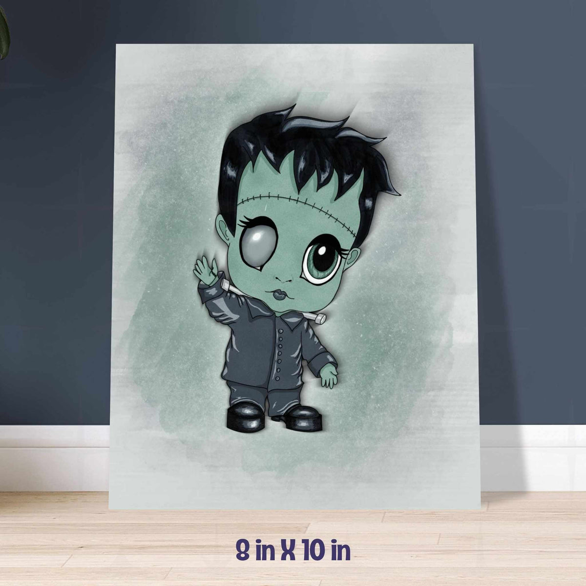 Frankenstein art print in the 8x10 inch size, leaning against a navy blue wall on a light wood floor.