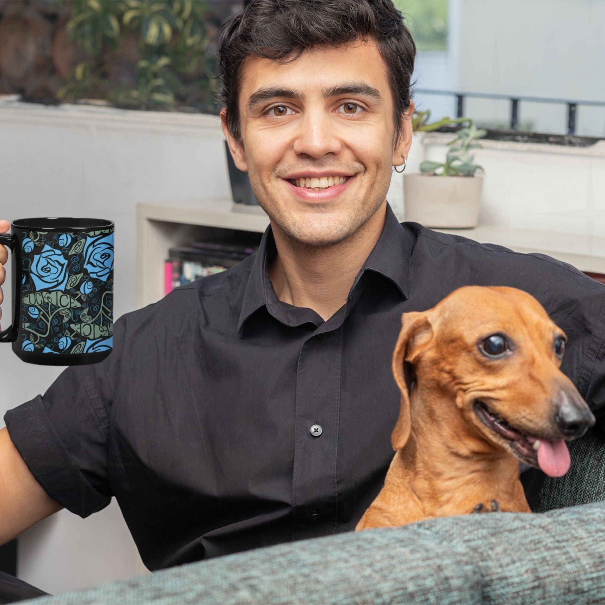 Man holding a dark floral hidden message coffee mug while sitting with a dachshund, mug features cornflower blue roses and Fuck ICE hidden in sage green leaf lettering on a black ceramic wrap-around print