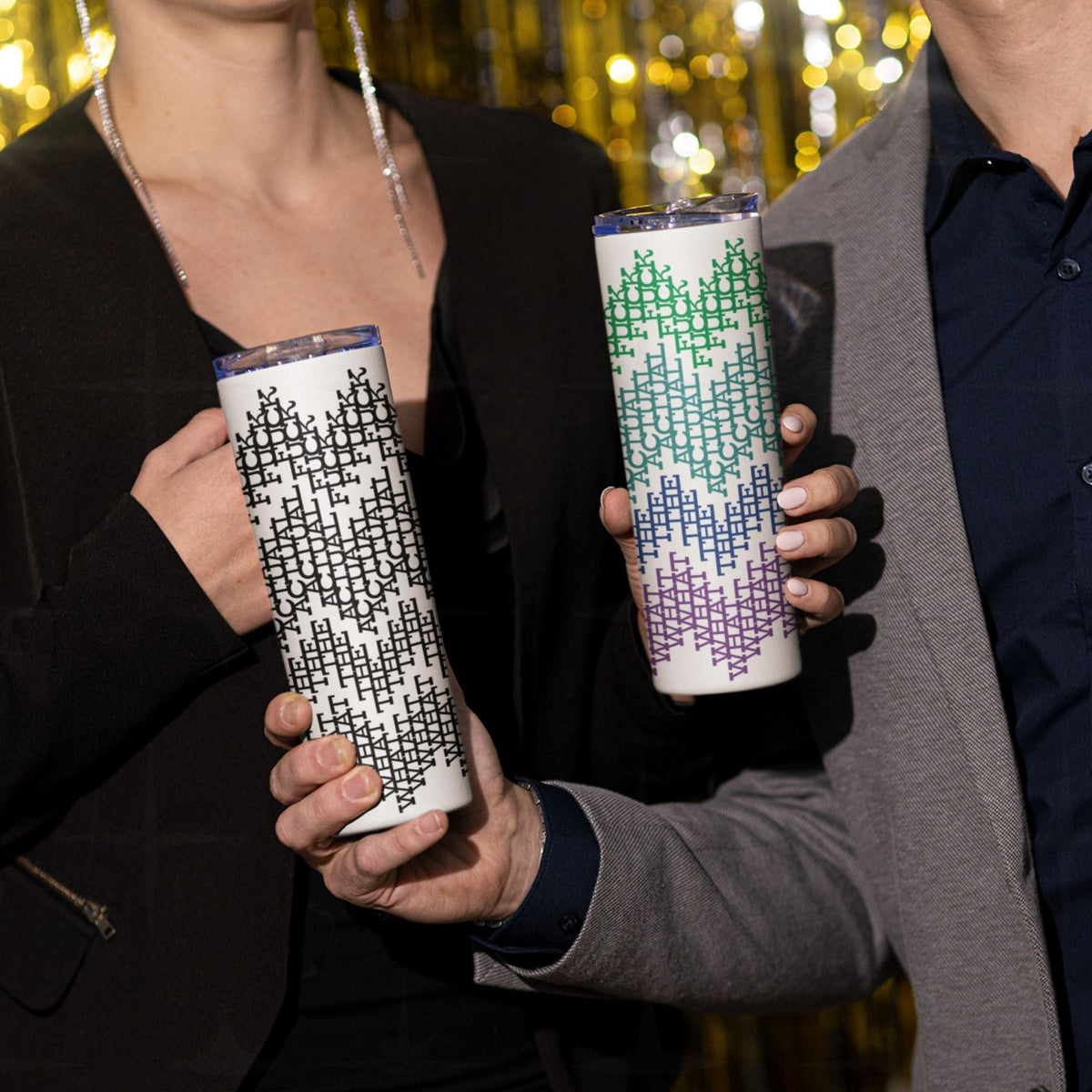 Two people holding the black stripes and bright stripes What The Actual Fuck hidden message tumblers at a party with gold tinsel in the background