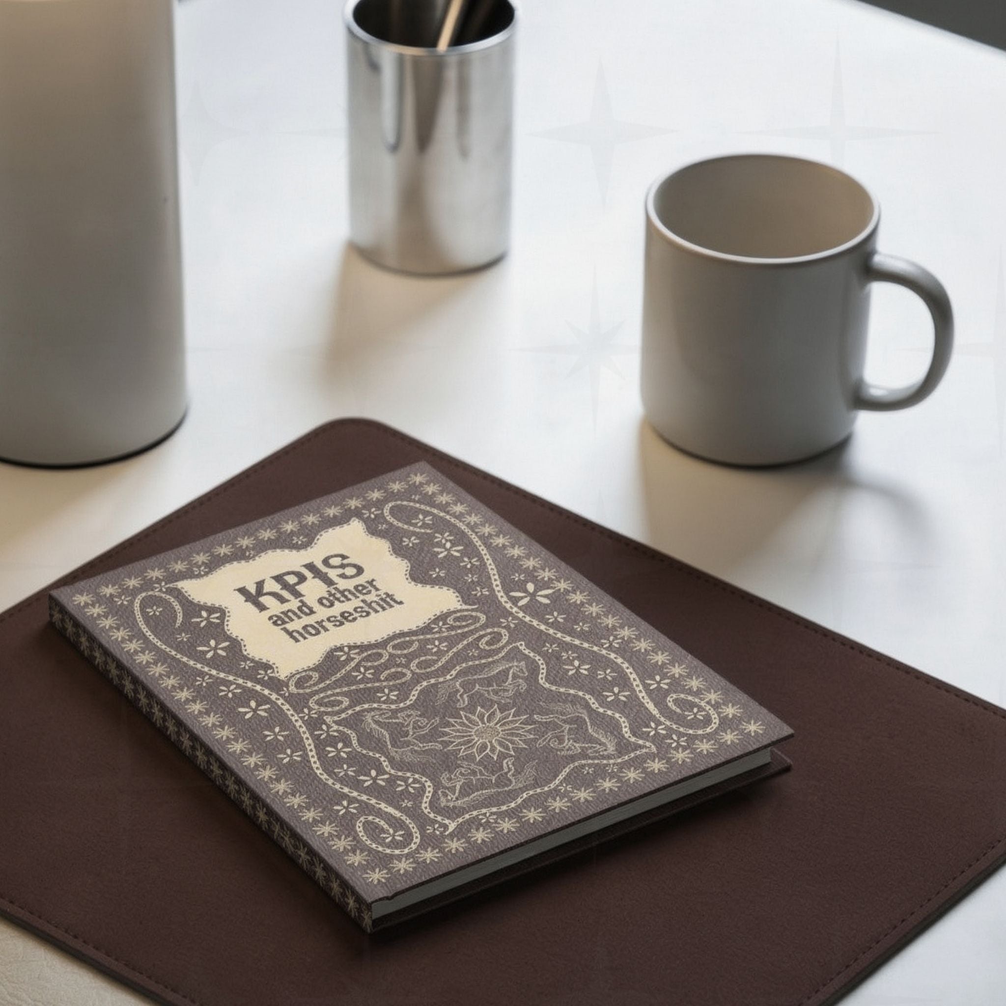 Funny KPI profanity journal on brown leather desk pad beside coffee mug and pen holder in office desk lifestyle setting