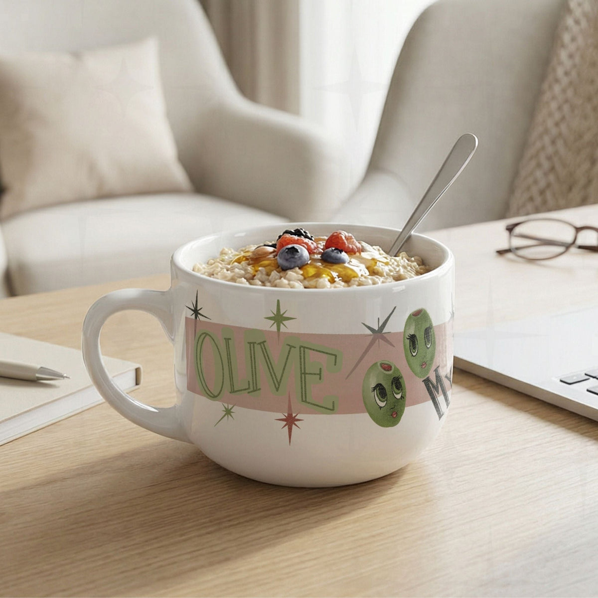 25oz funny mom latte mug filled with oatmeal and berries on a wood desk with notebook and pen, Olive My Kids Are Weird olive pun design visible on white ceramic body